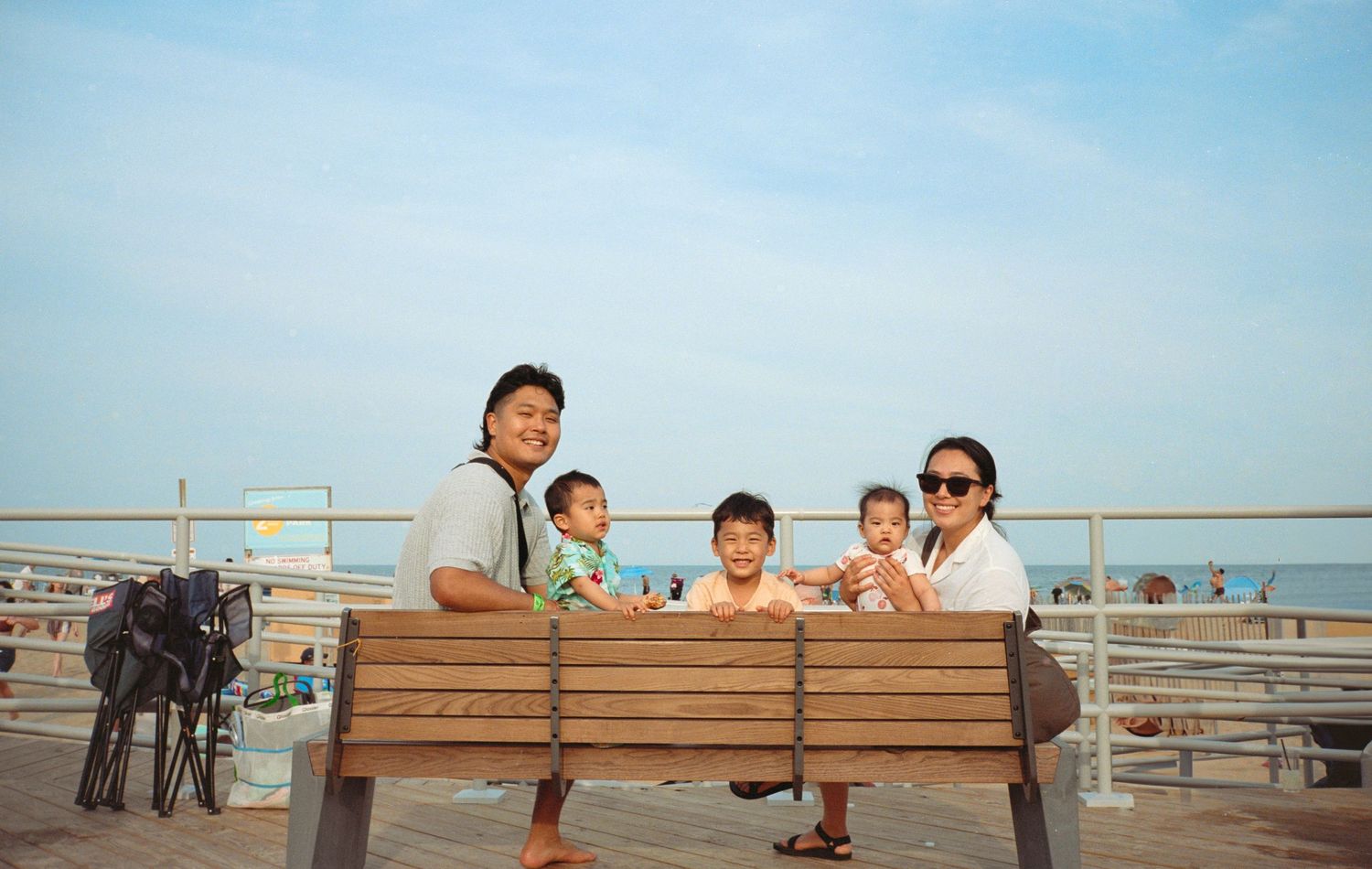People relaxing on wooden benches at a beachfront boardwalk.