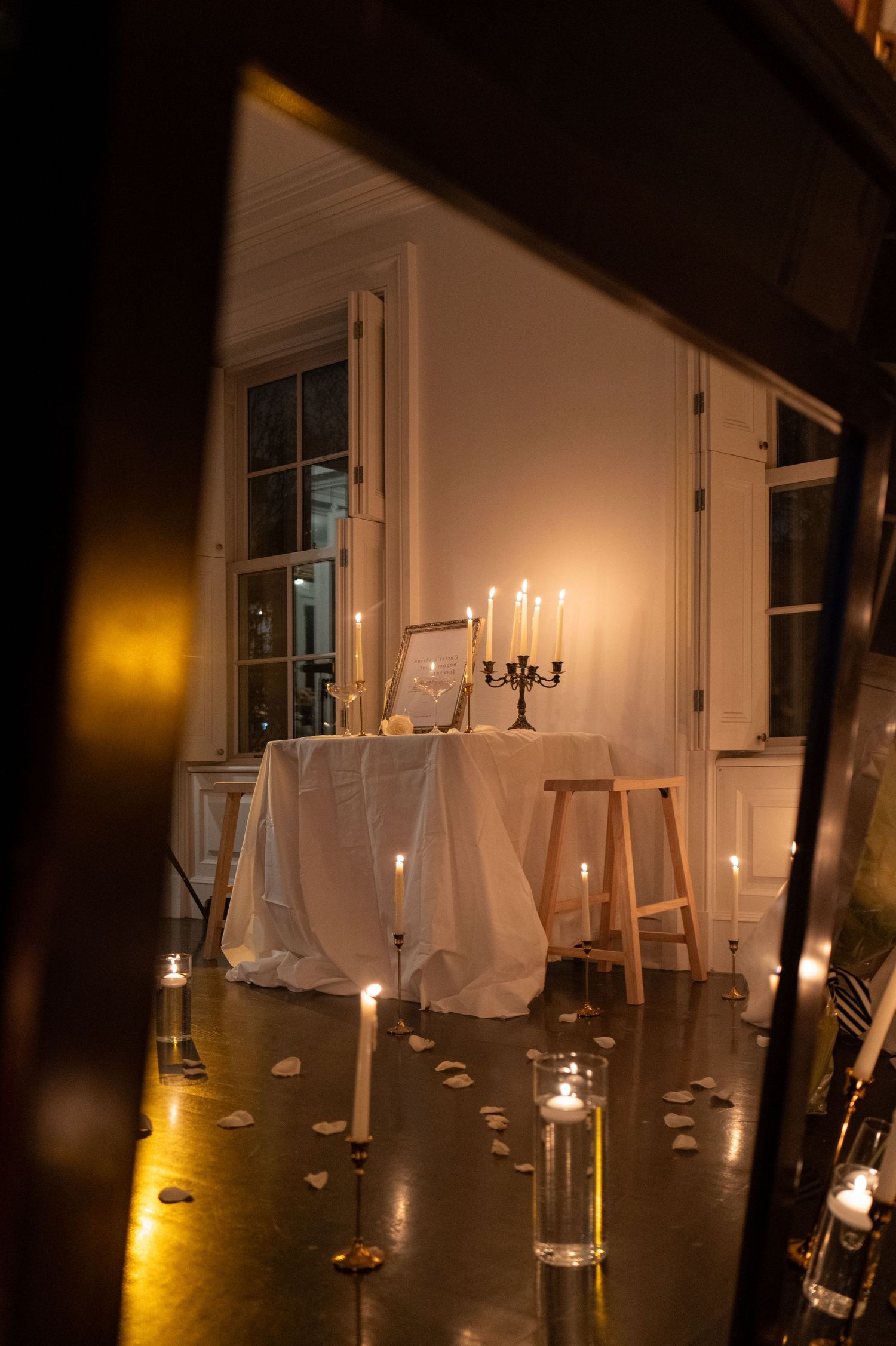 White candles glowing in glass holders create an elegant ambiance in a dimly lit room.