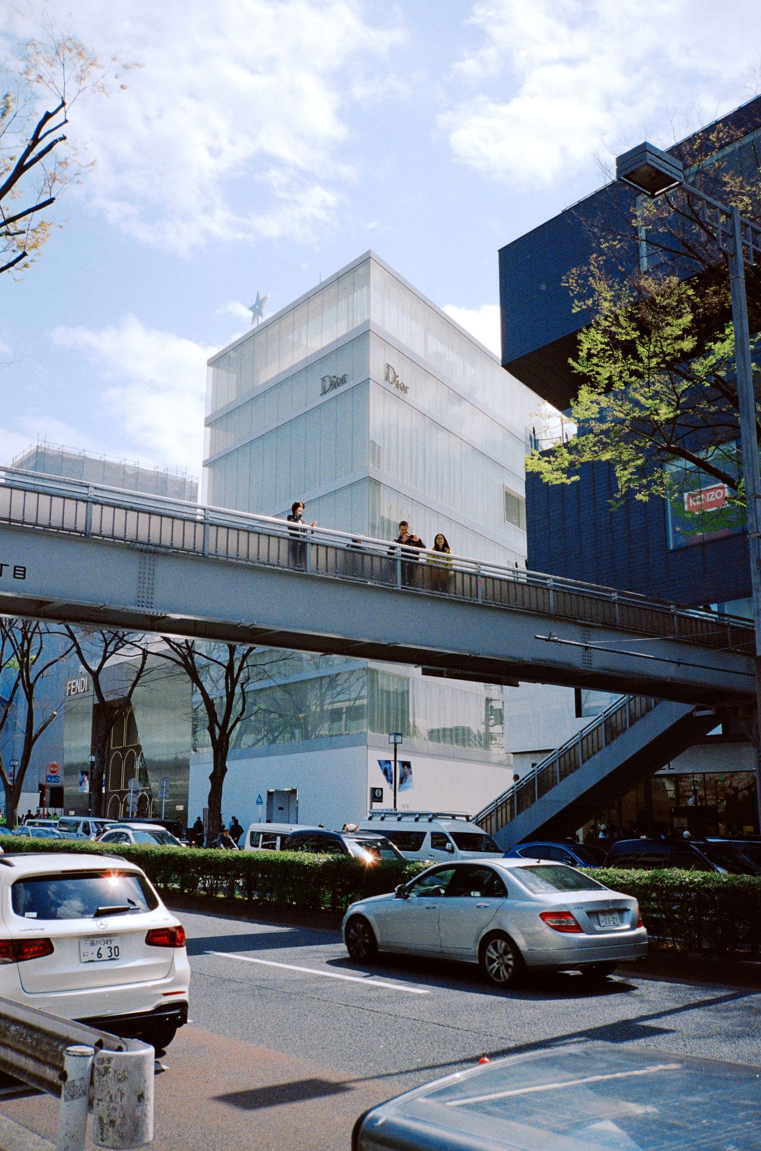 Modern white commercial building with exterior staircases and parked cars.