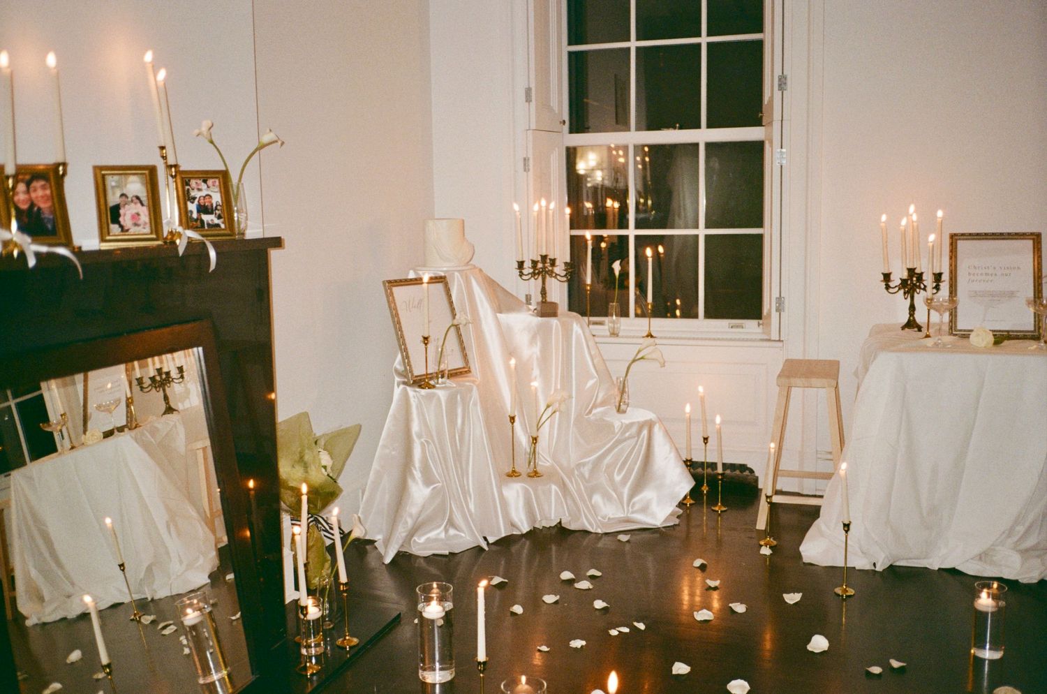 Elegant indoor venue decorated with white drapes and glowing candle arrangements.