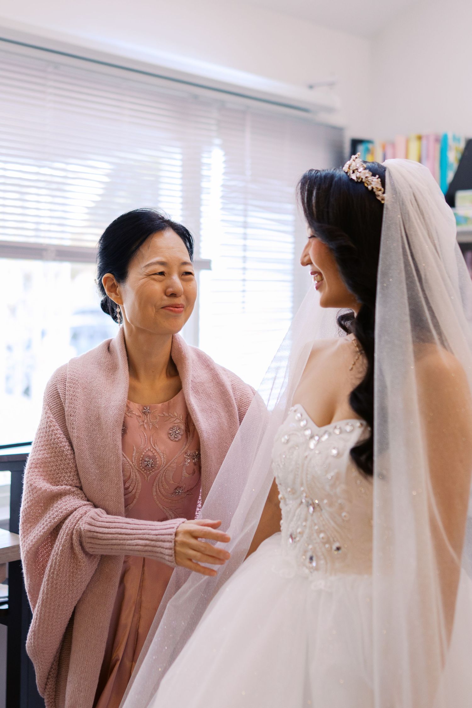 Tender moments shared during wedding preparations in a sunlit room with bookshelves.
