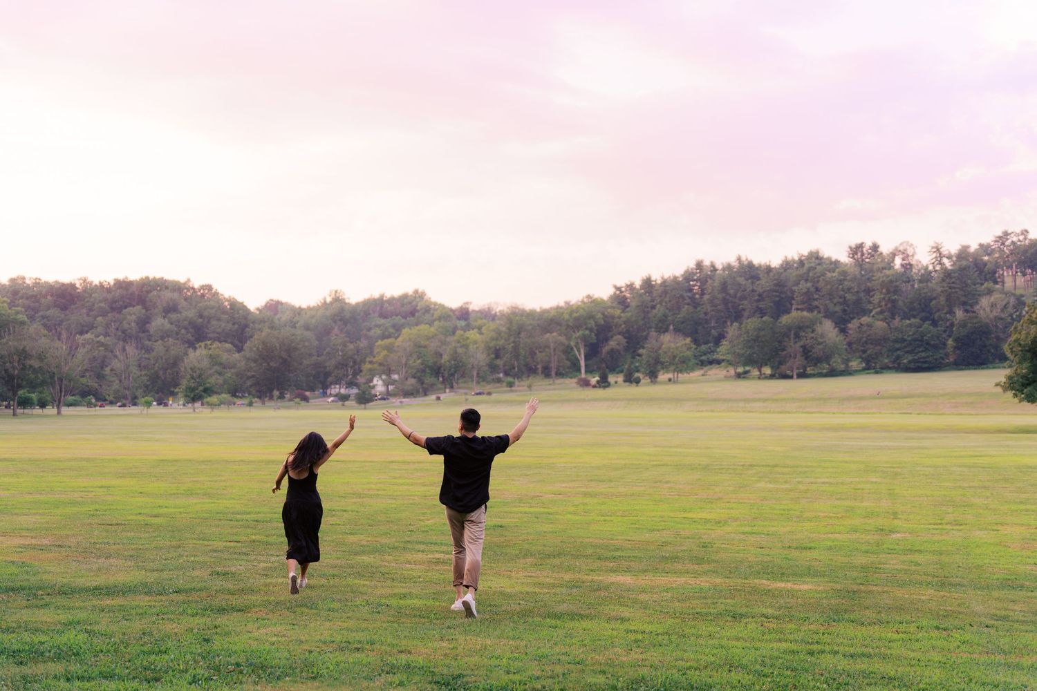 Silhouettes of people walking across a vast open field at dusk.