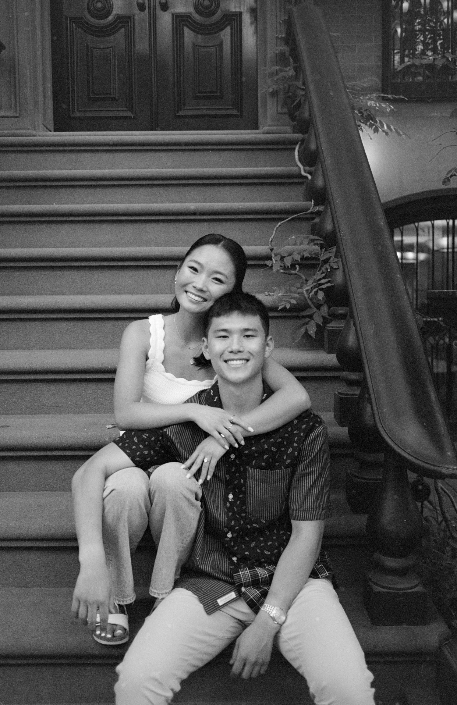 Two people sharing a playful moment while sitting on outdoor steps.