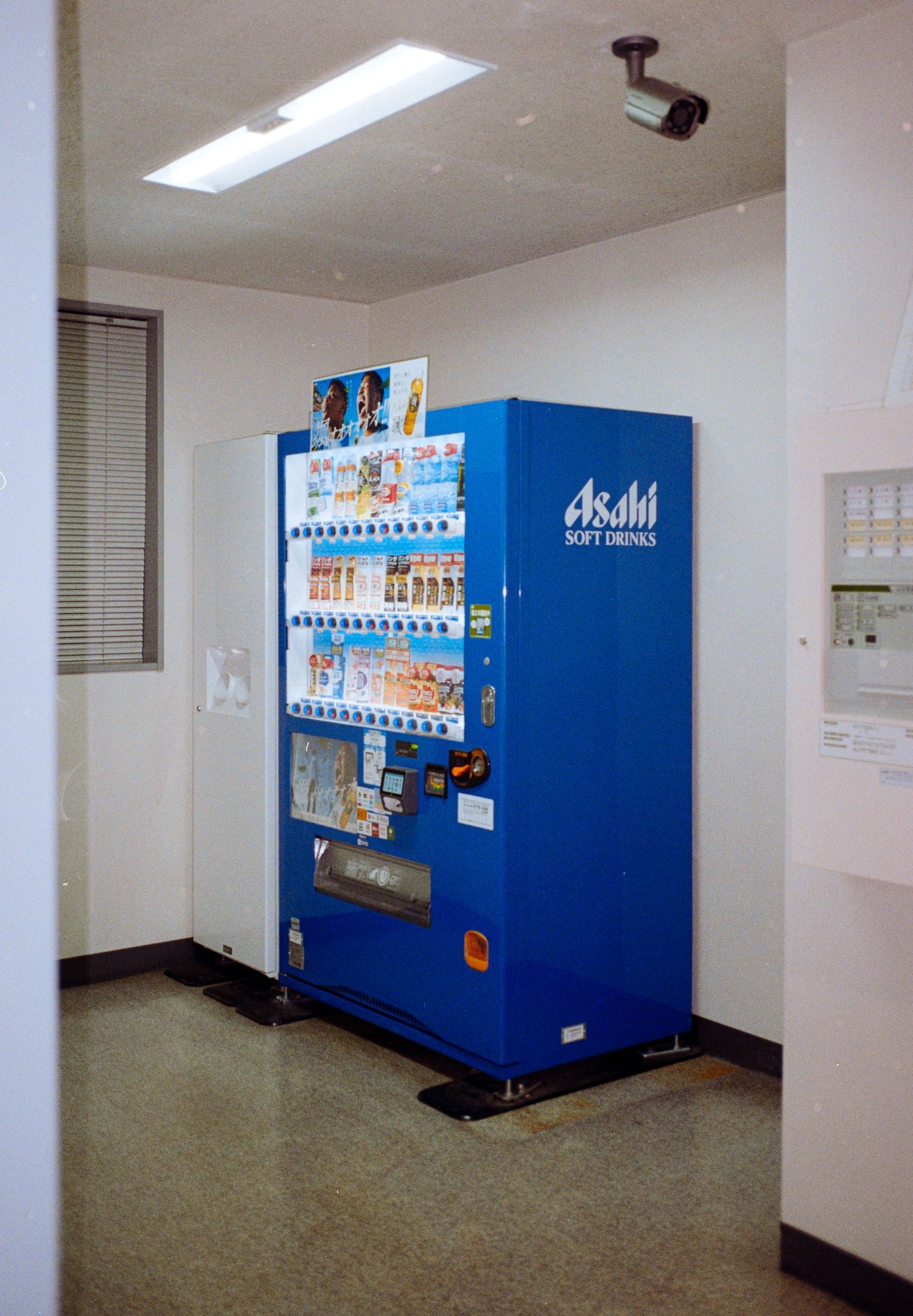 Interior hallway with blue vending machines against white walls in a Japanese building.