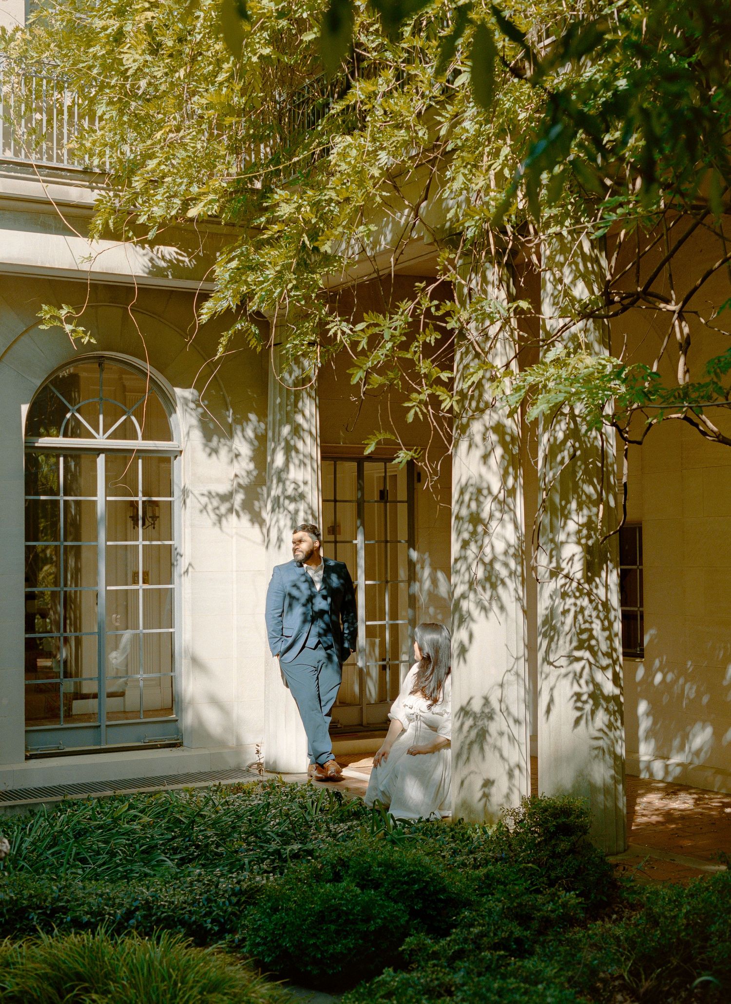 An elegant building exterior with arched windows and climbing vines in warm sunlight.