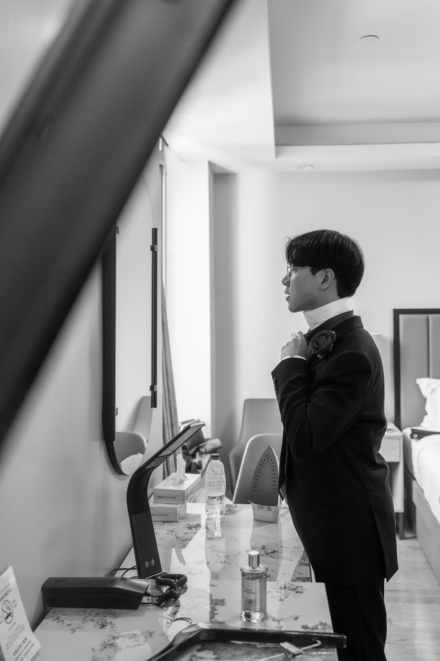 Black and white candid shots showing wedding preparation moments in a bright room.