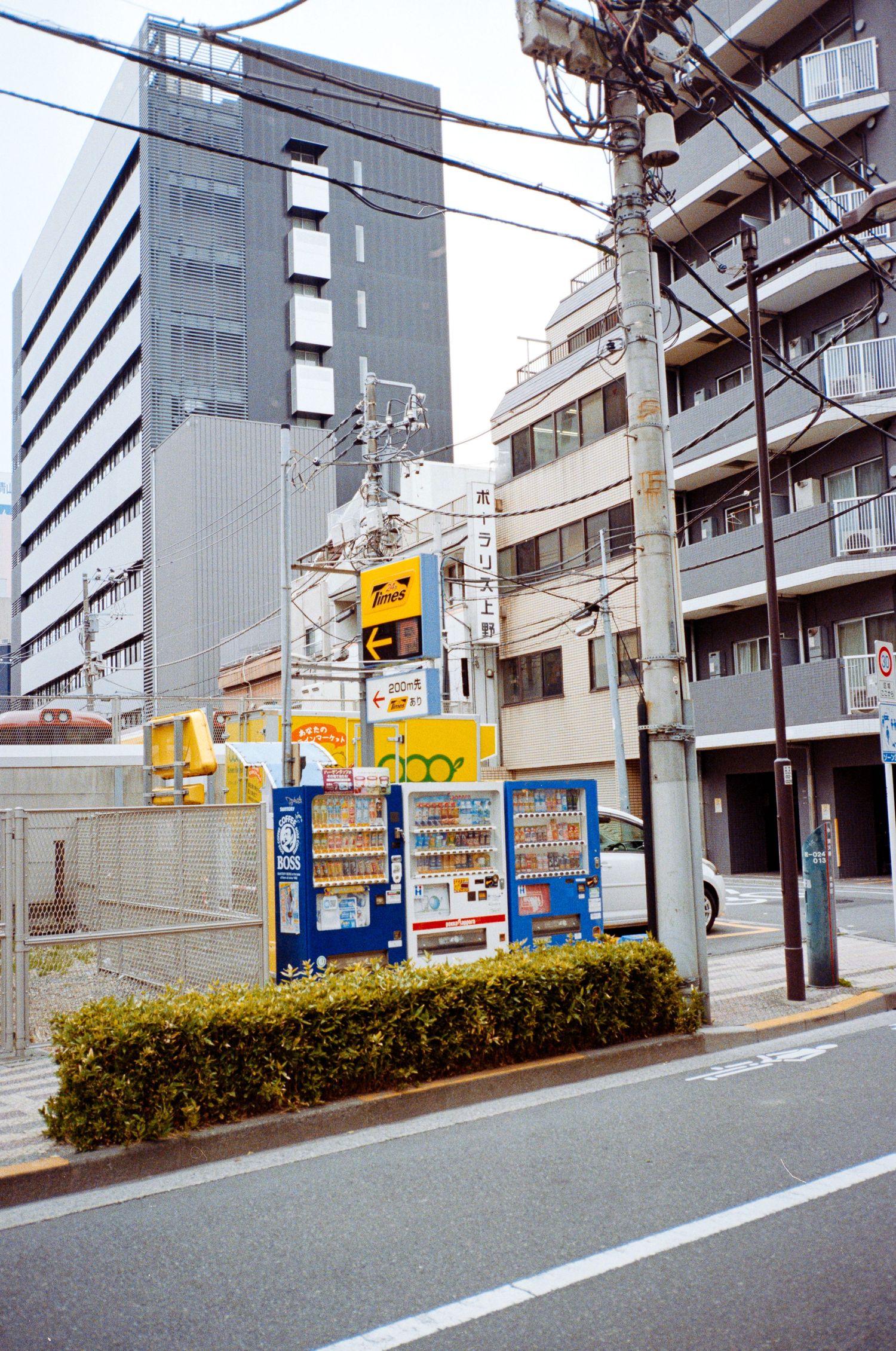 Urban street view in Japan showing apartment buildings and commercial signage along a quiet road.