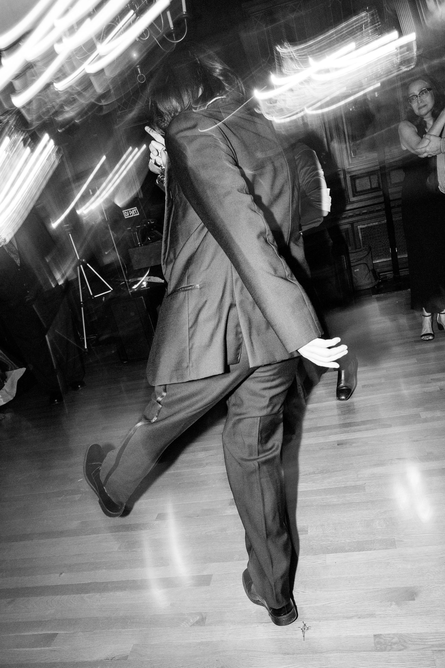 A sequence of black and white photos showing a dancer performing energetic swing dance moves on a polished dance floor.