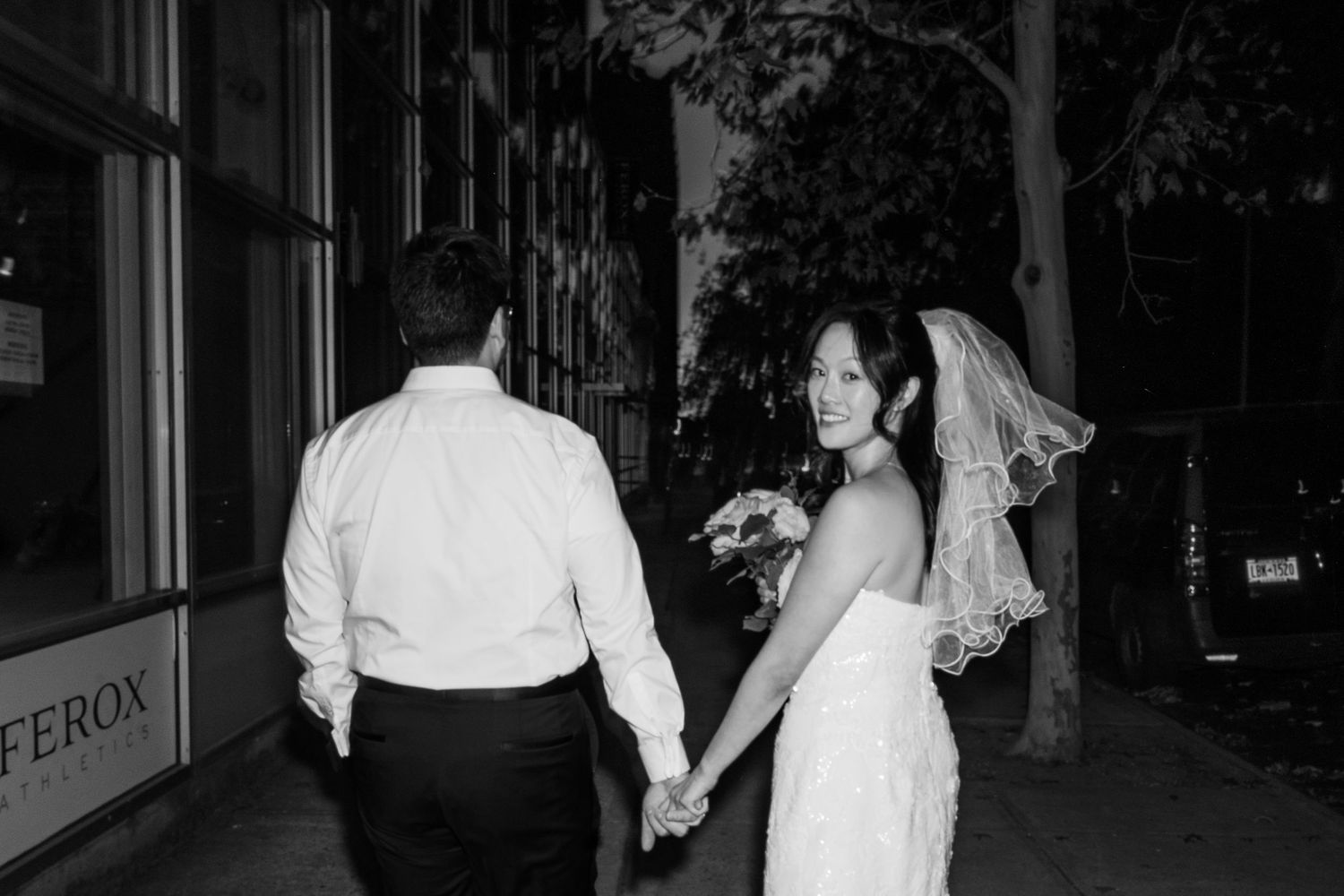 A nighttime wedding scene with couples walking along a brick-lined path.