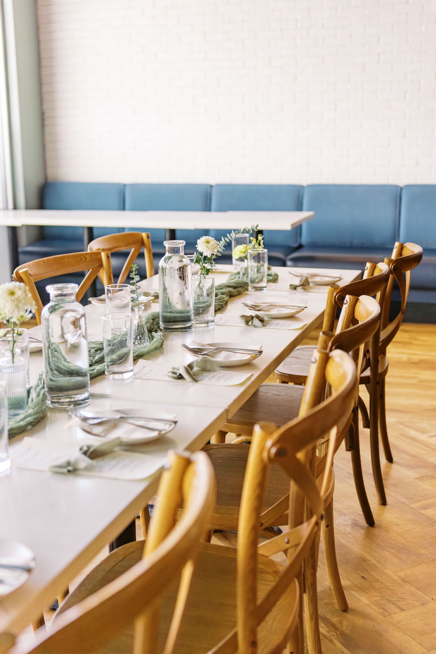 Elegant wedding reception table setup with wooden chairs and minimalist place settings.