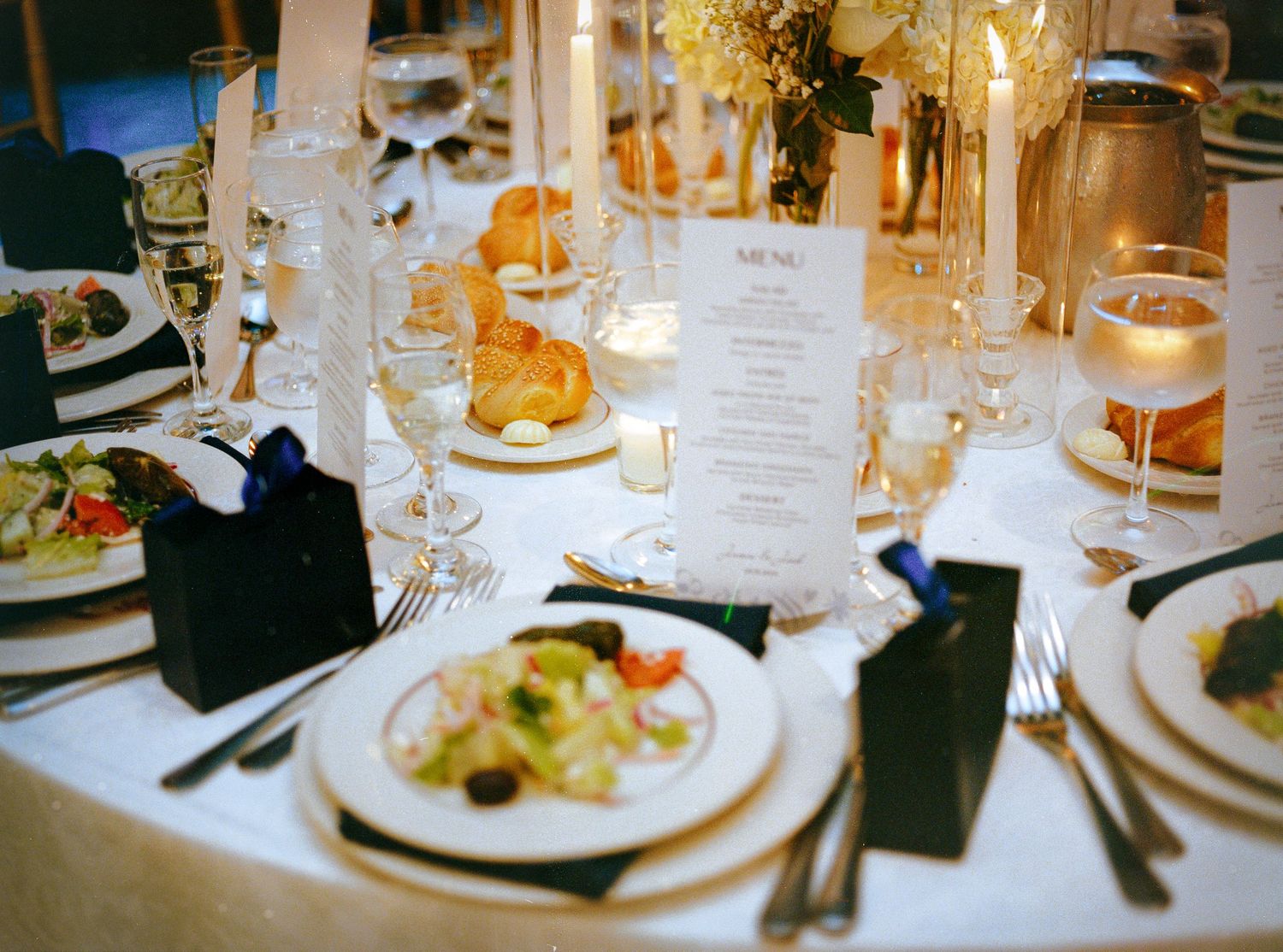 Close-up of elegant wedding reception place settings with menu cards and glassware.