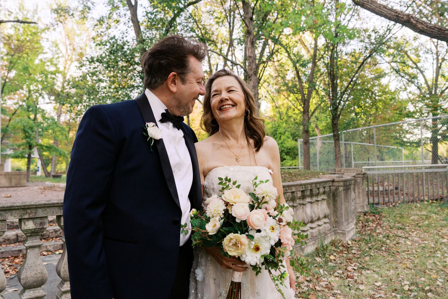 Romantic outdoor wedding photos taken in a wooded park setting with natural lighting and greenery.