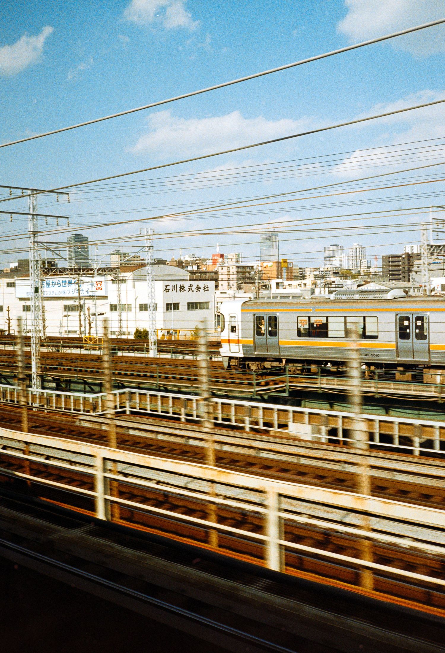 Train tracks and railway infrastructure stretching across an urban landscape under blue skies.