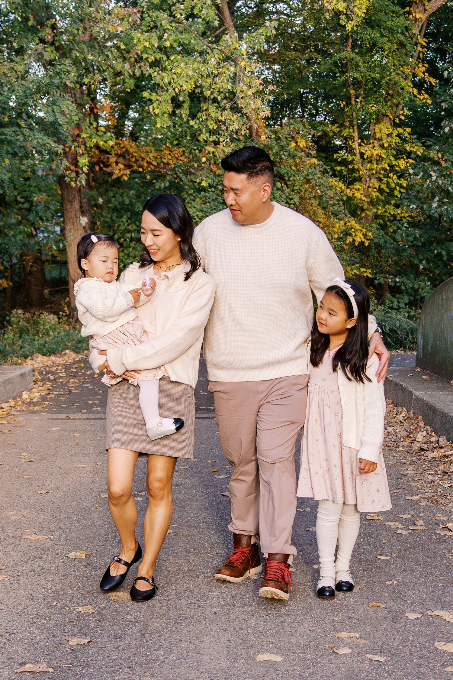 Family walking together in coordinated neutral outfits on an autumn path.