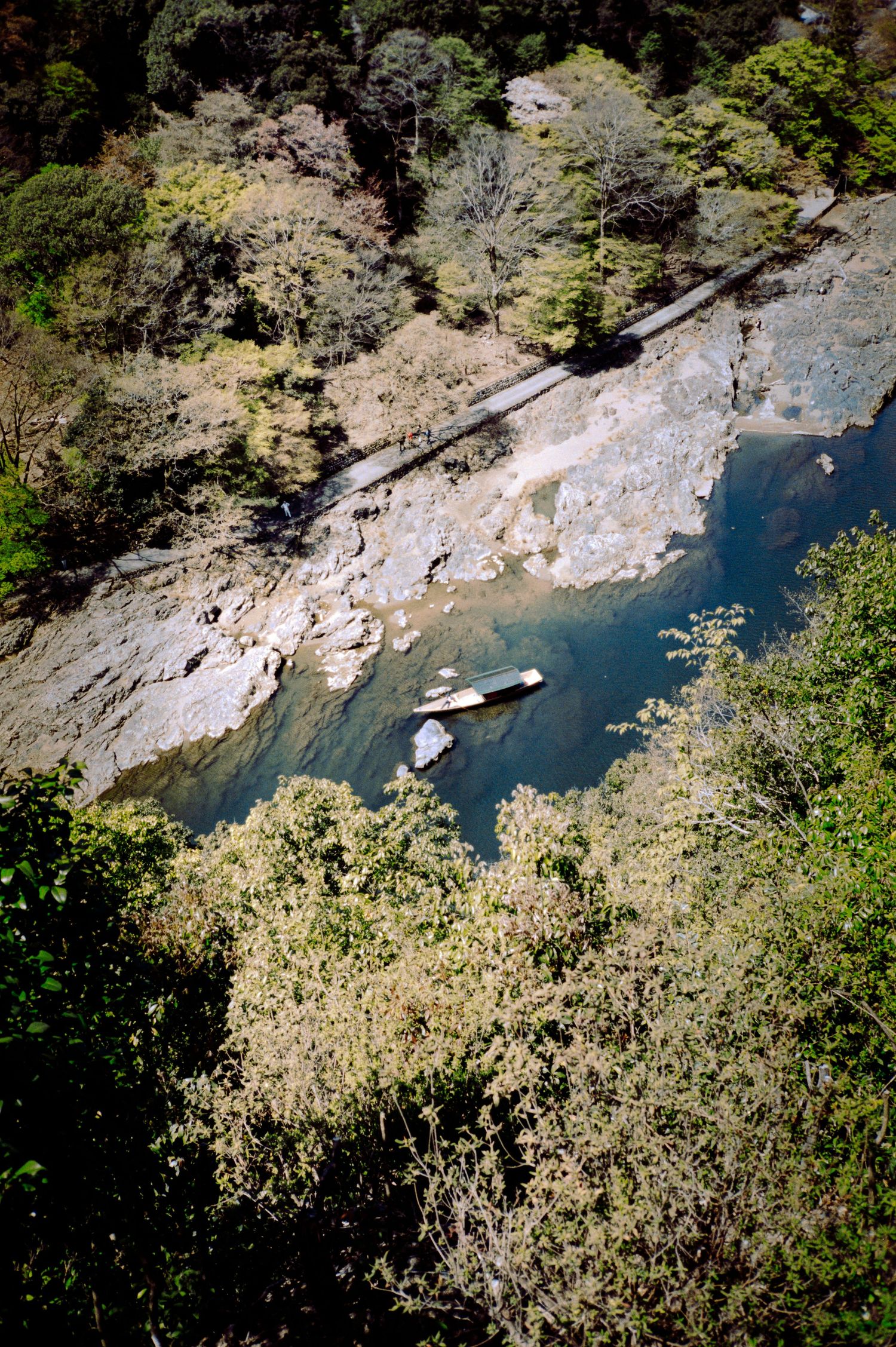 Aerial view of boats on a blue river surrounded by rocky cliffs and forest.