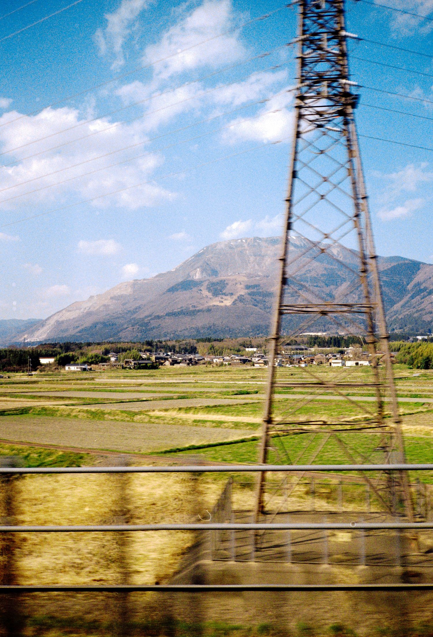 Mountain landscape with electrical transmission tower and rural fields in Japan.