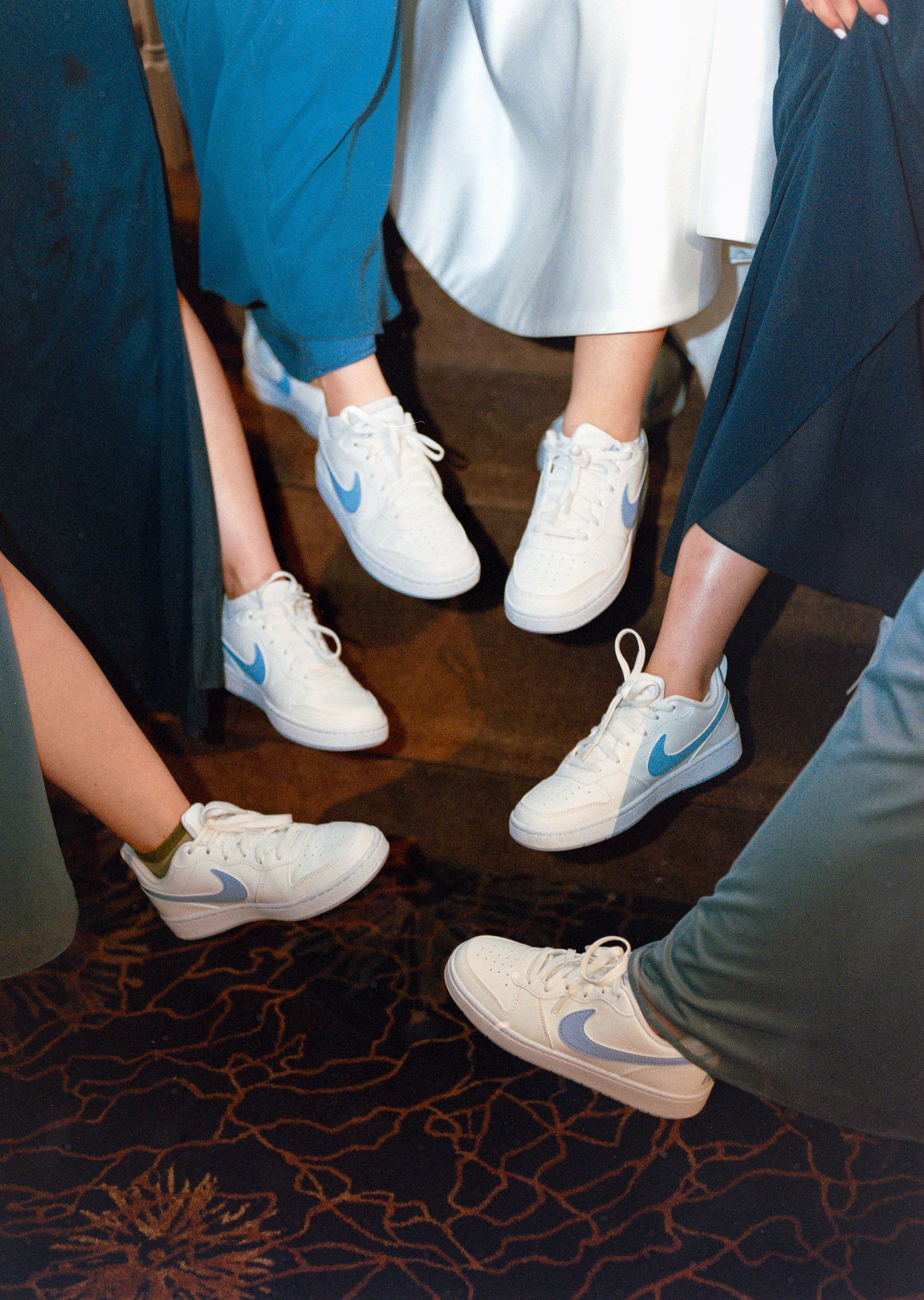 Group wearing coordinated Nike sneakers on patterned carpet floor.