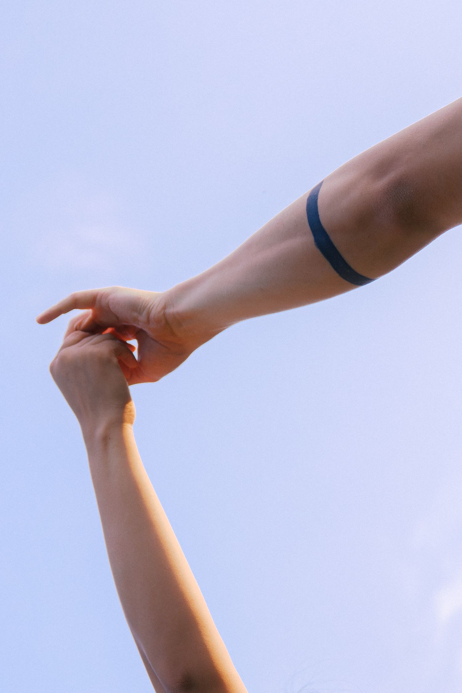 Close-up sequence of hands making gestures against a bright blue sky.