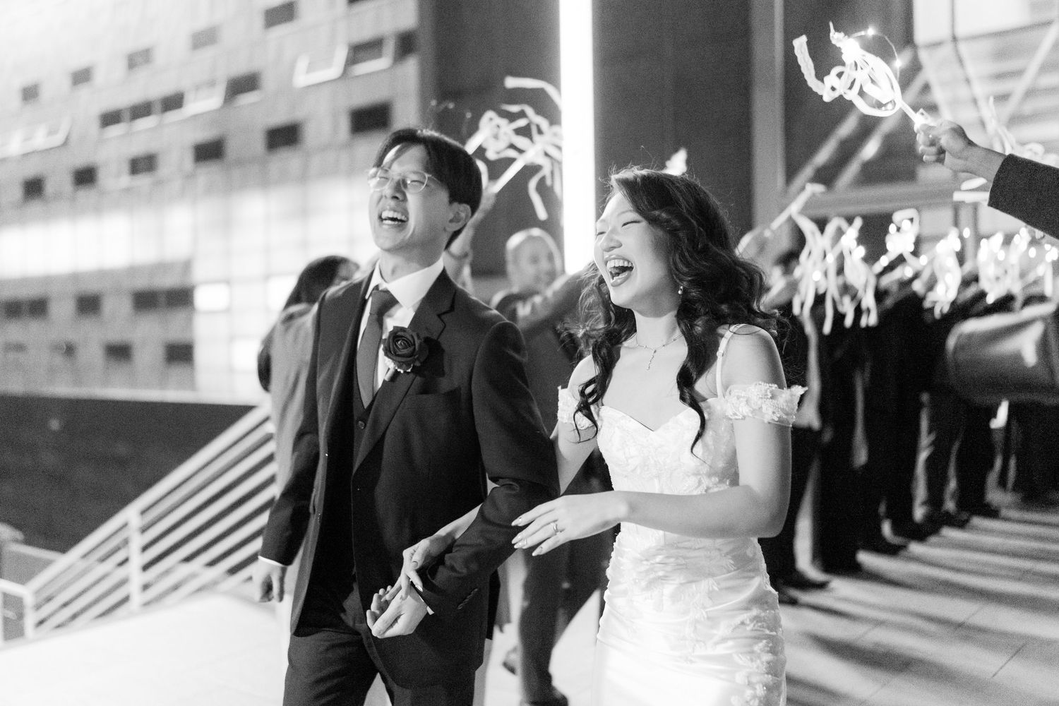 Wedding guests line up holding sparklers to create a glowing pathway for celebration.