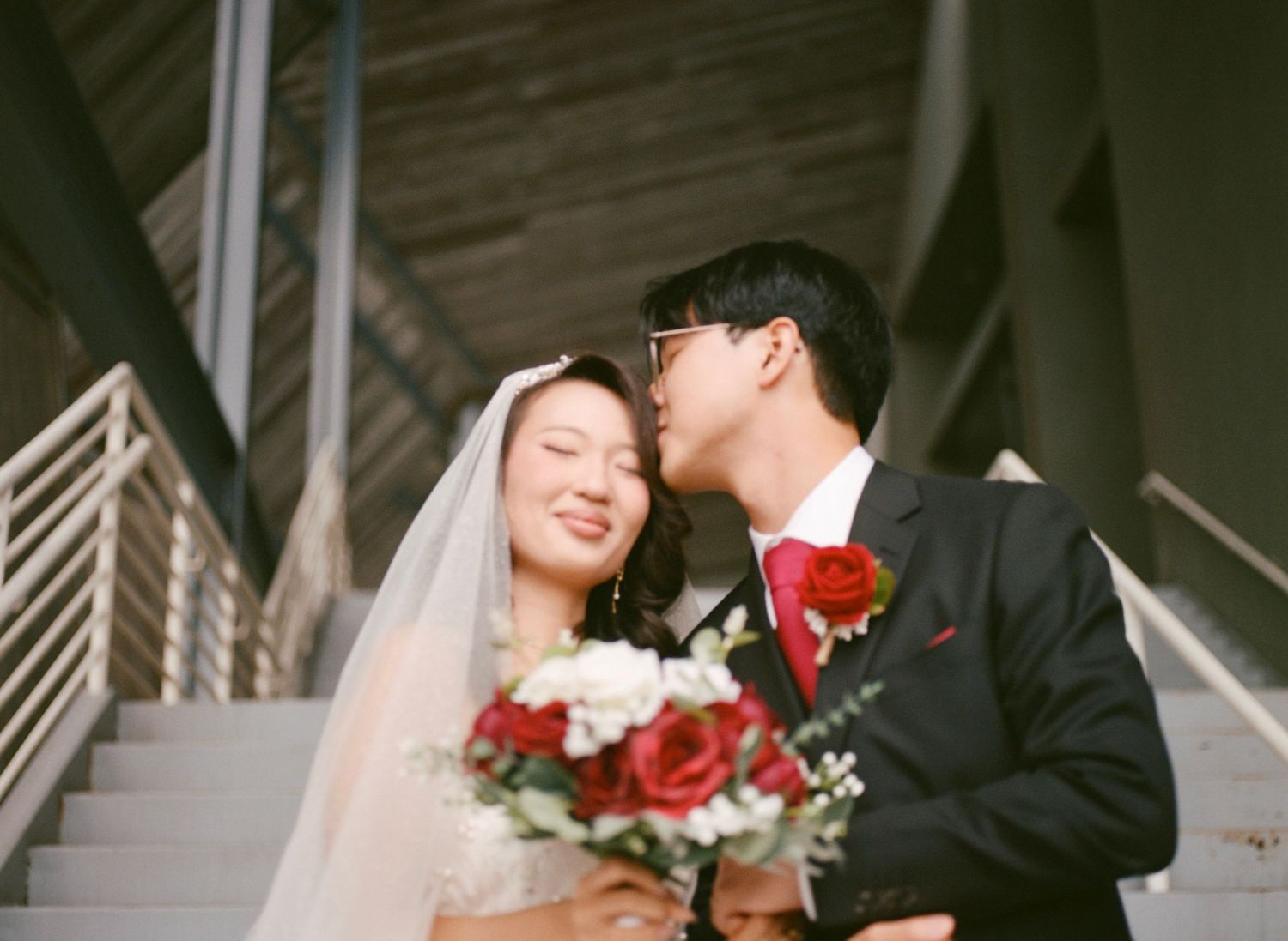 Couple sharing romantic moments on a staircase in wedding attire.