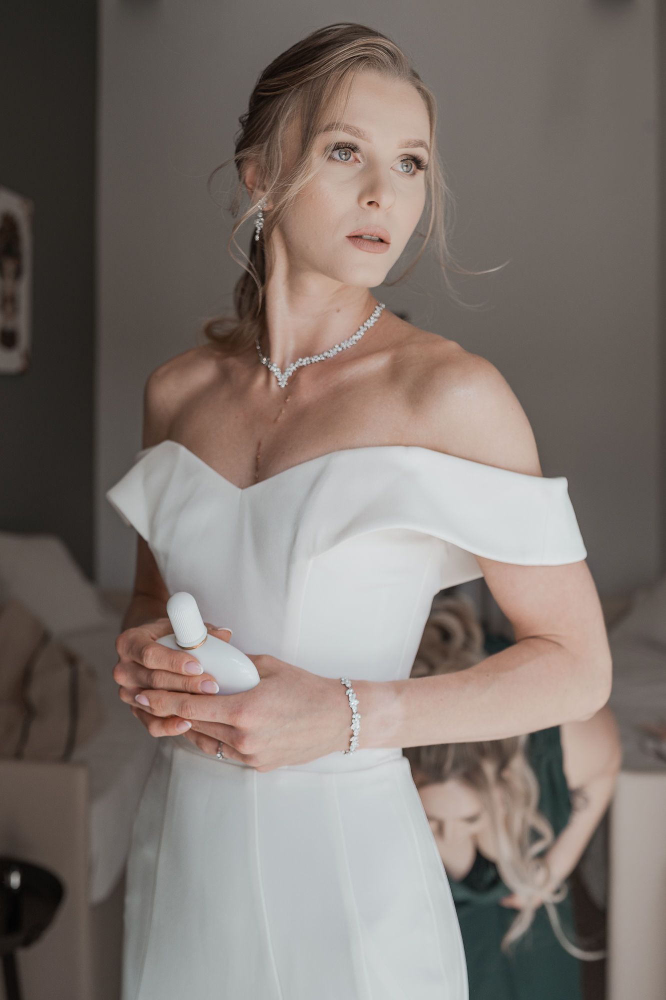 Elegant off-shoulder white wedding dress with delicate jewelry and soft styling details.