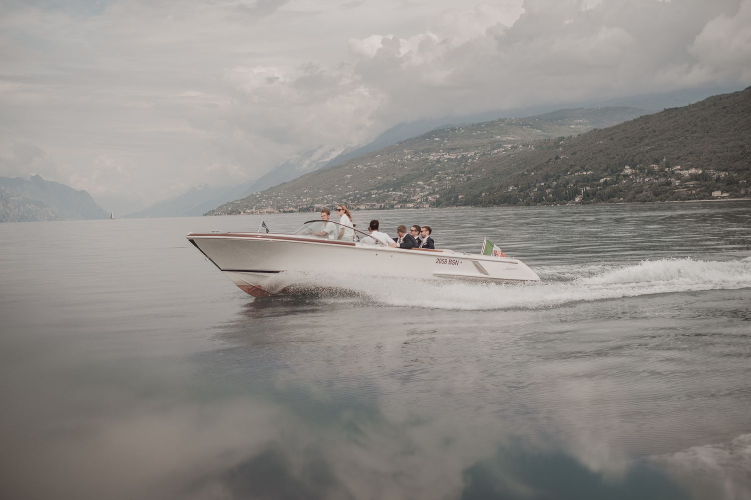 Speedboat cruising across a misty mountain lake with passengers enjoying the ride.