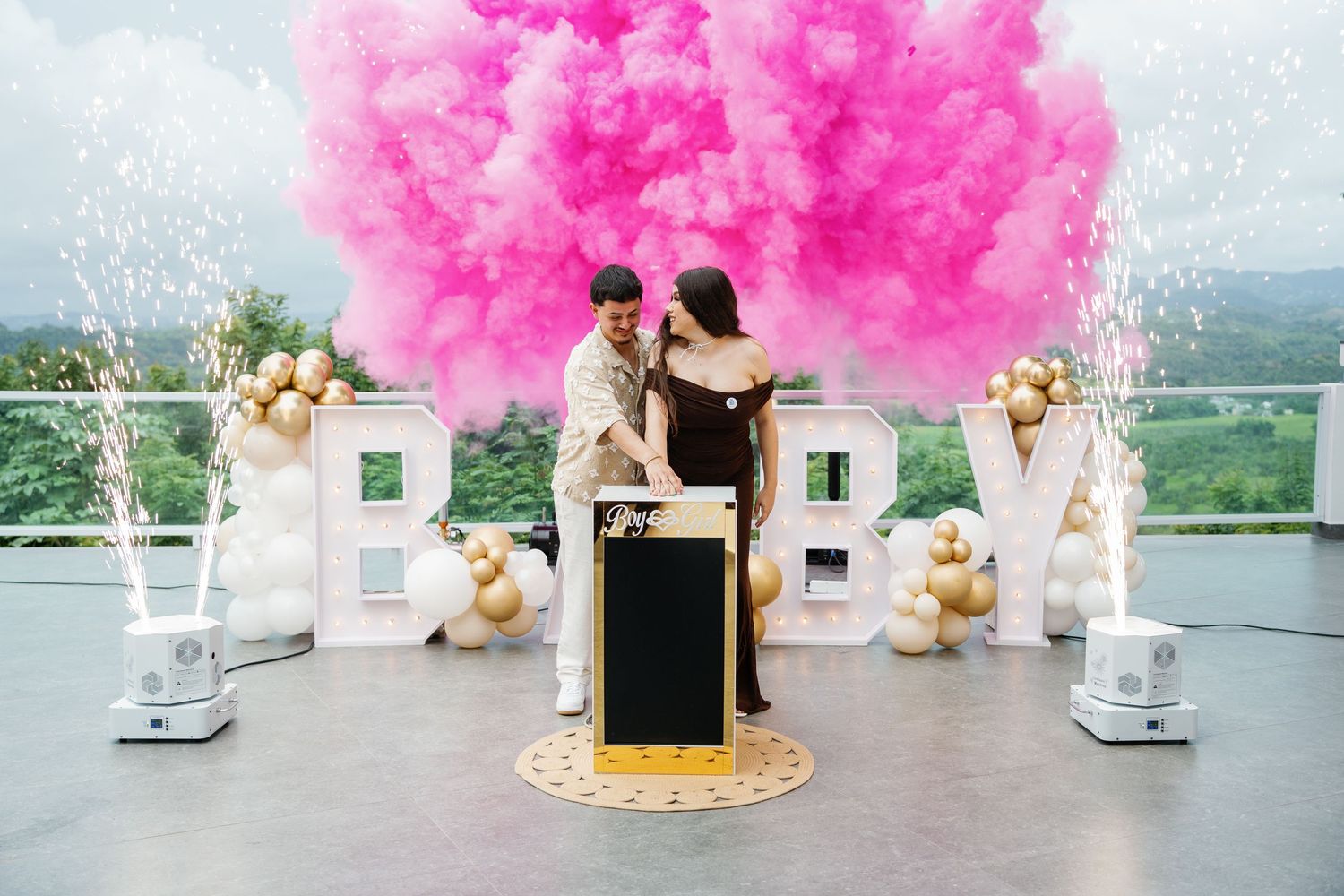 Pink smoke effect creates dramatic backdrop for party decorations and gold accents.