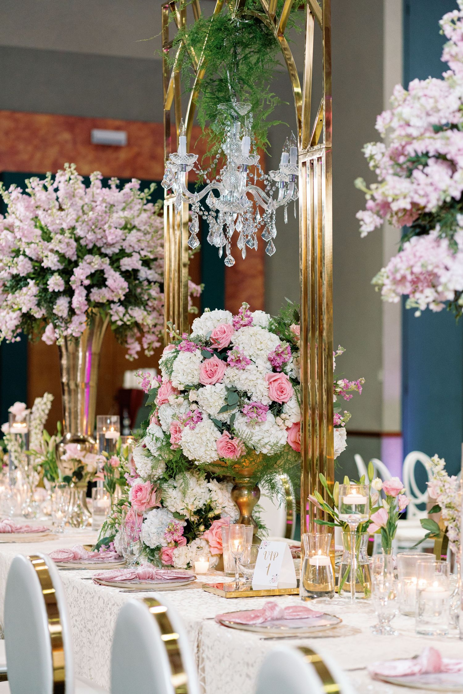Elegant table setting with gold candelabras, pink flowers, and crystal accents.