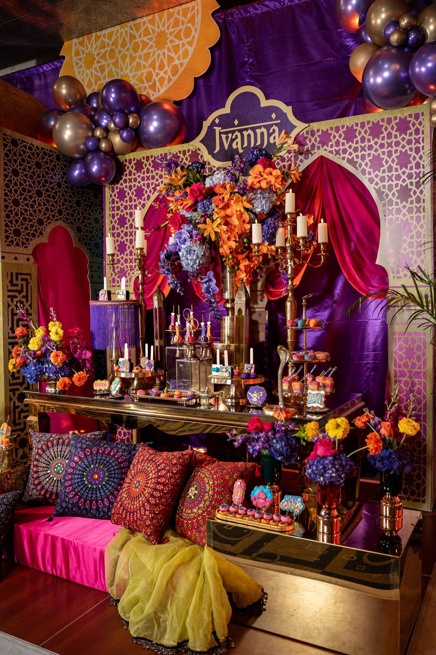 Vibrant purple and orange themed party decor with balloons and ornate patterns.
