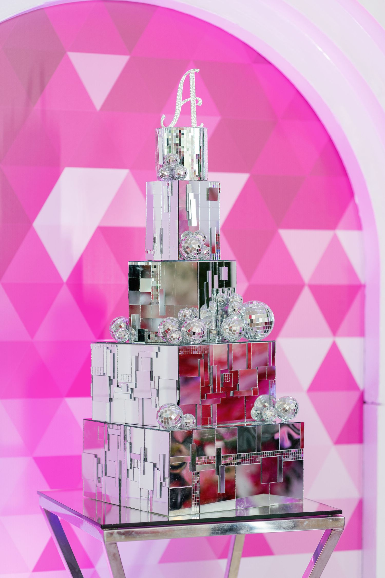 Modern mirrored geometric display setup against a pink geometric backdrop.