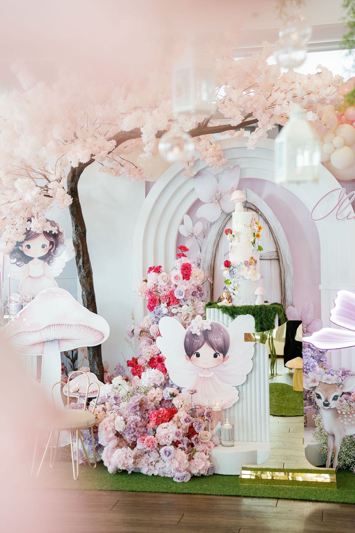 Dreamy pink cherry blossom themed party setup with white arches and floral decorations.