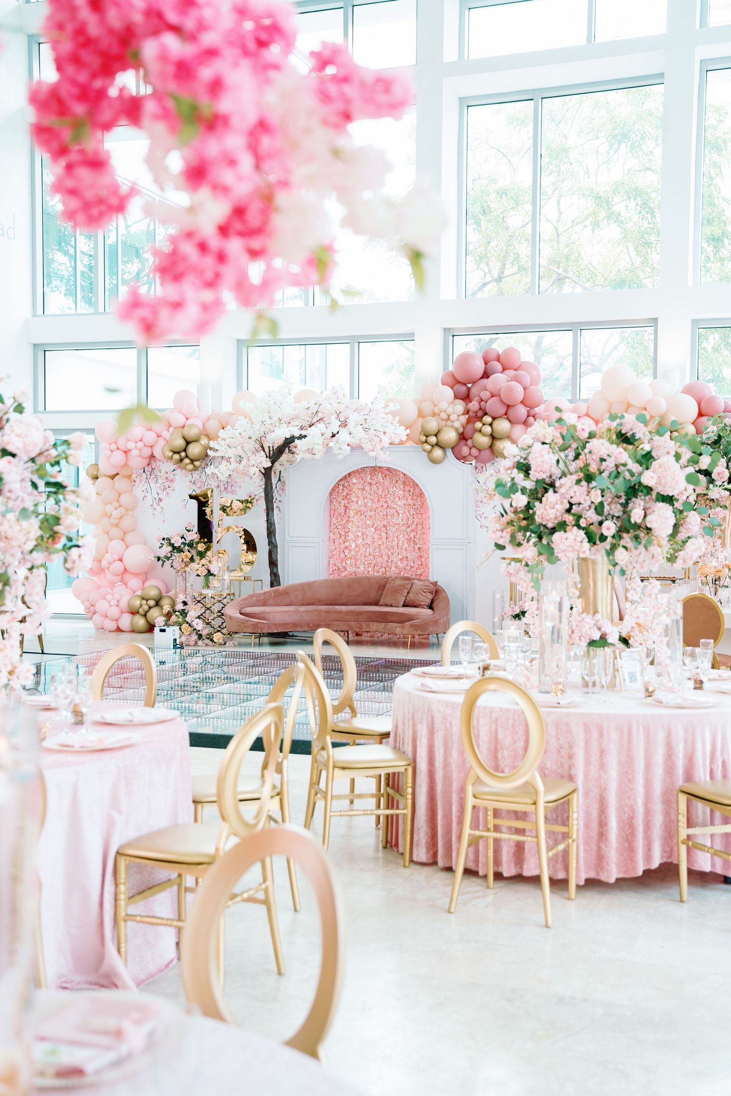 Romantic pink and gold themed wedding reception with round tables and floral decorations.