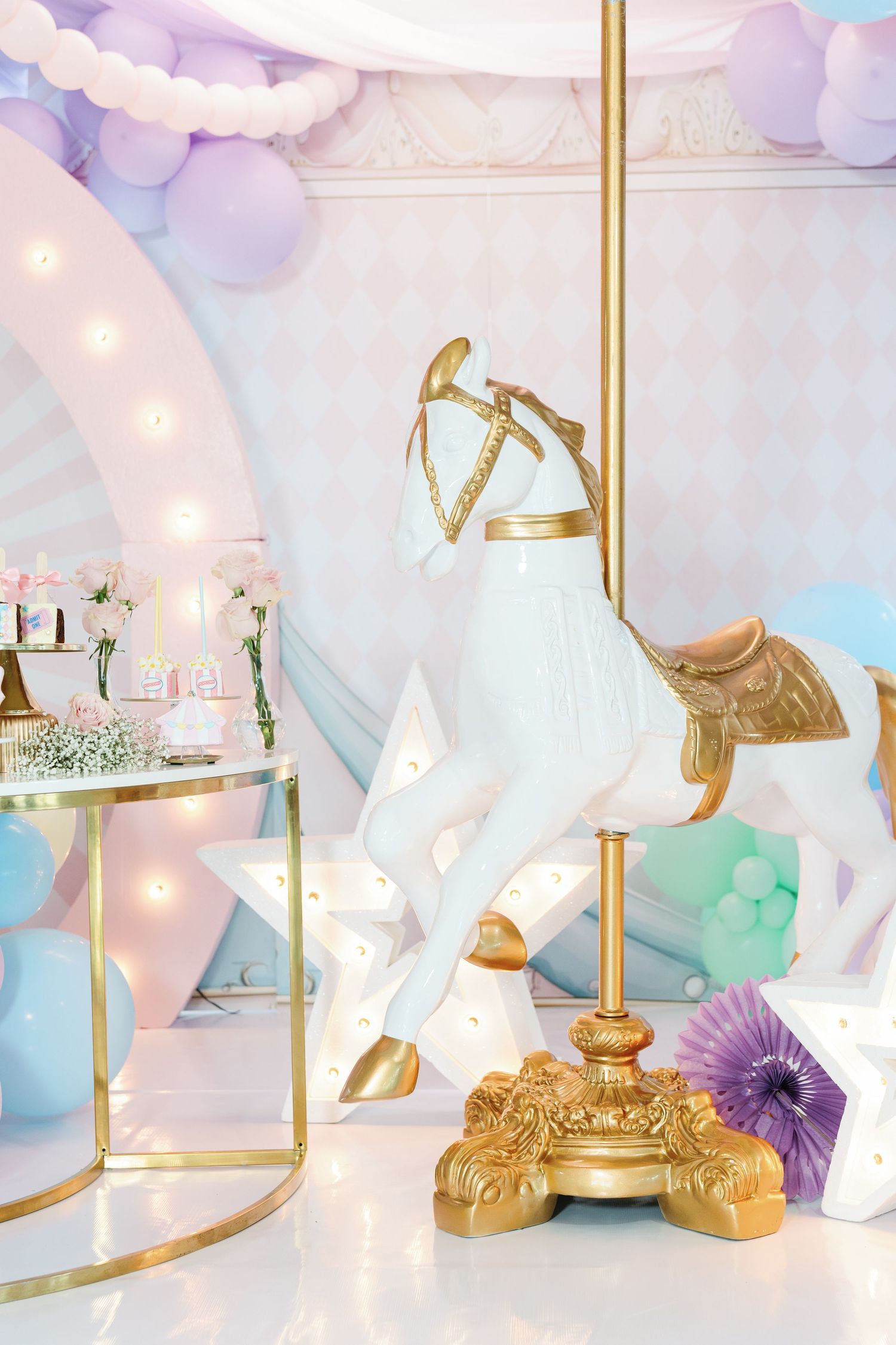 Elegant party setup with white angel wings, gold accents, and soft pastel balloon decorations.