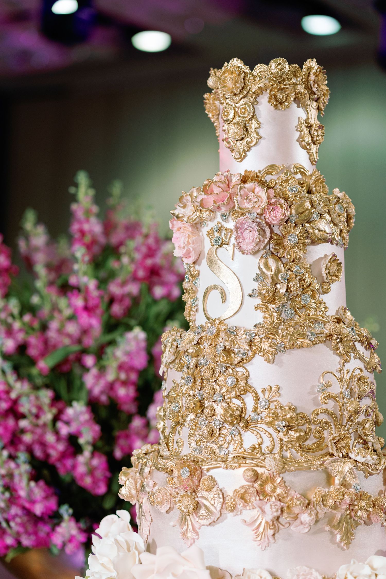 Ornate white and gold wedding cake decorated with intricate baroque-style details.