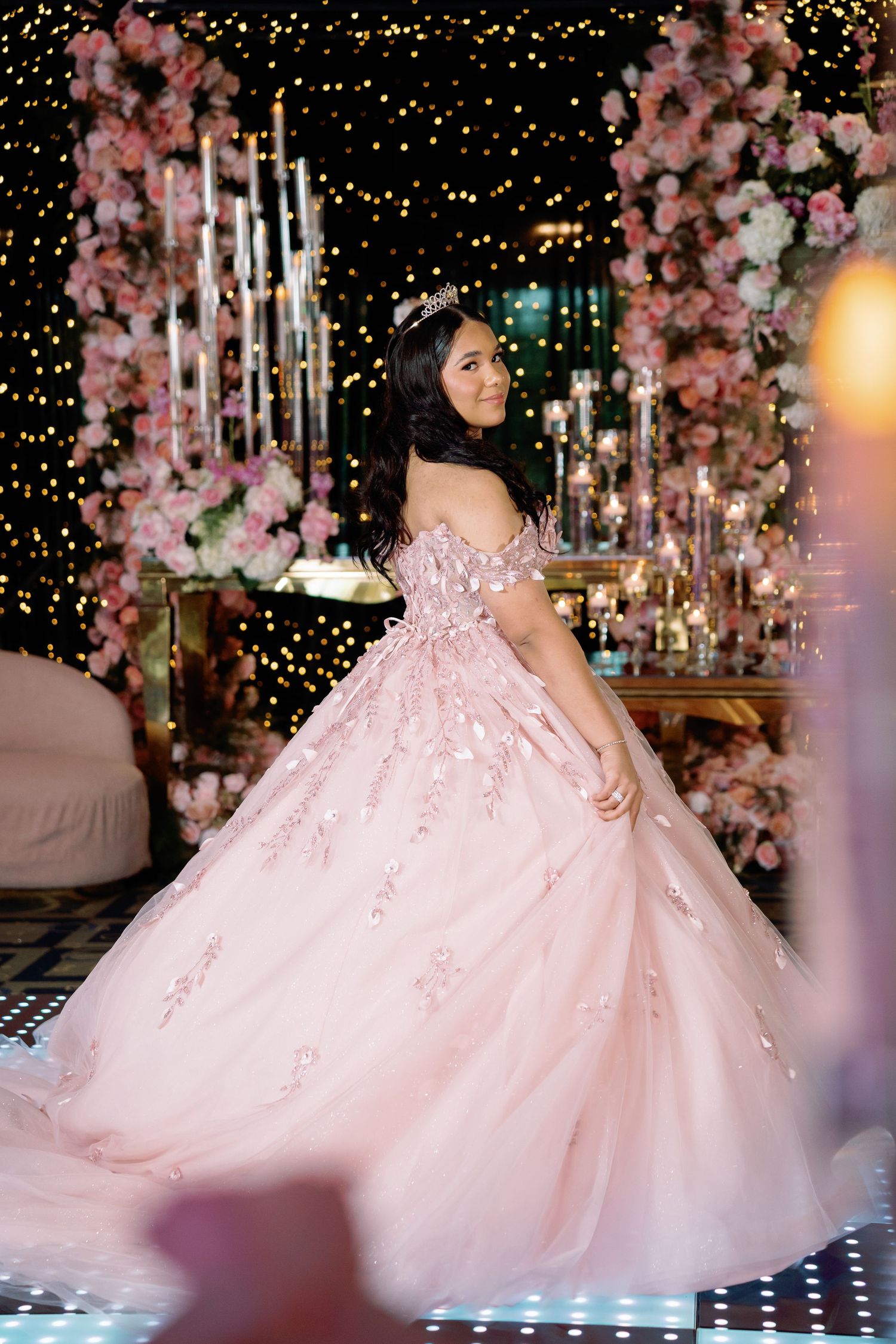 Luxurious pink ballgown photographed against a romantic backdrop of cherry blossoms and twinkling lights.