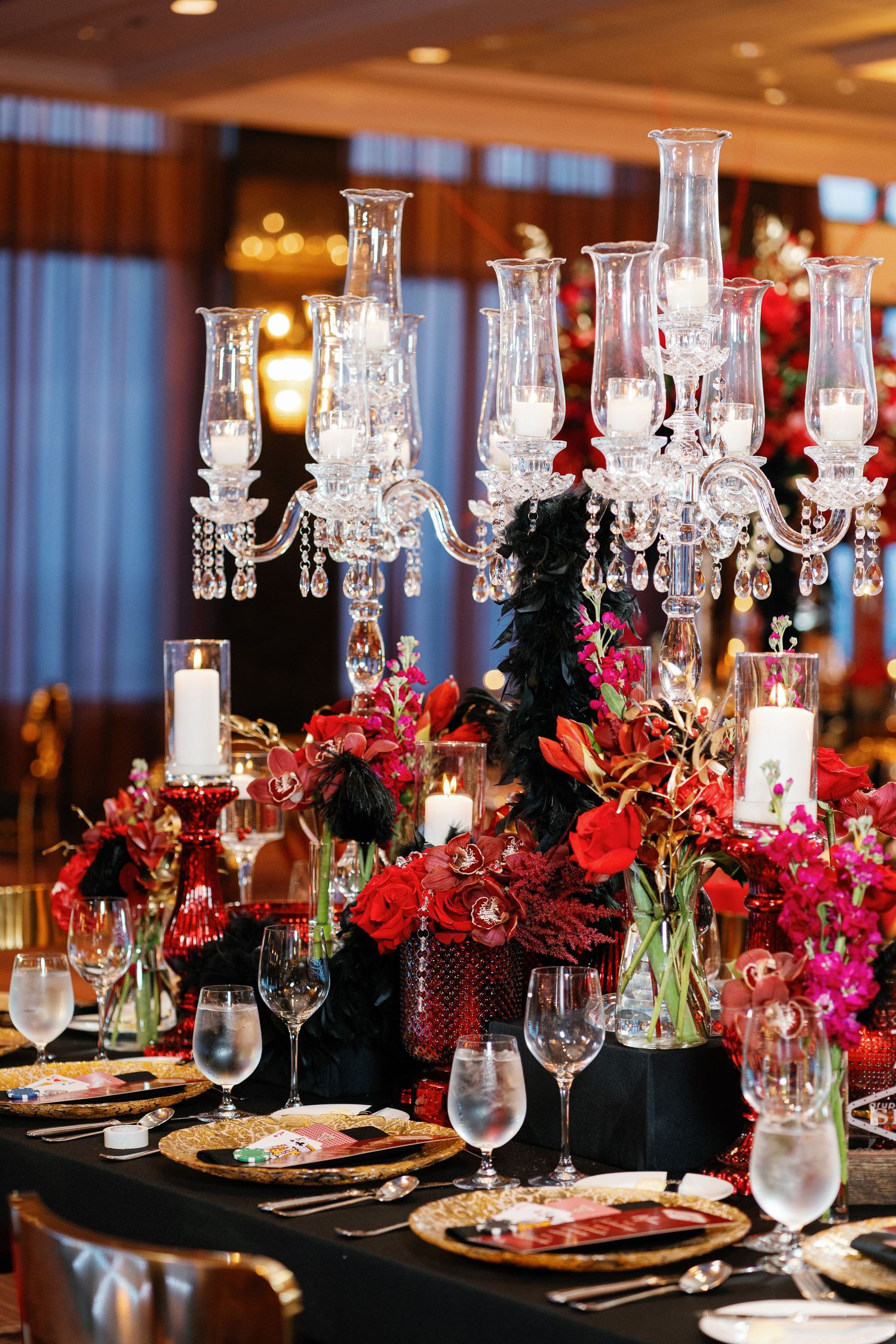 Dramatic red floral centerpieces with crystal candelabras on dark tablescapes for formal dining.