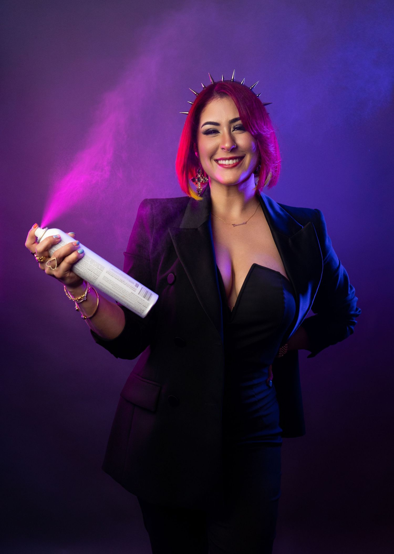 Professional beauty shot with purple lighting holding hair product in black blazer.