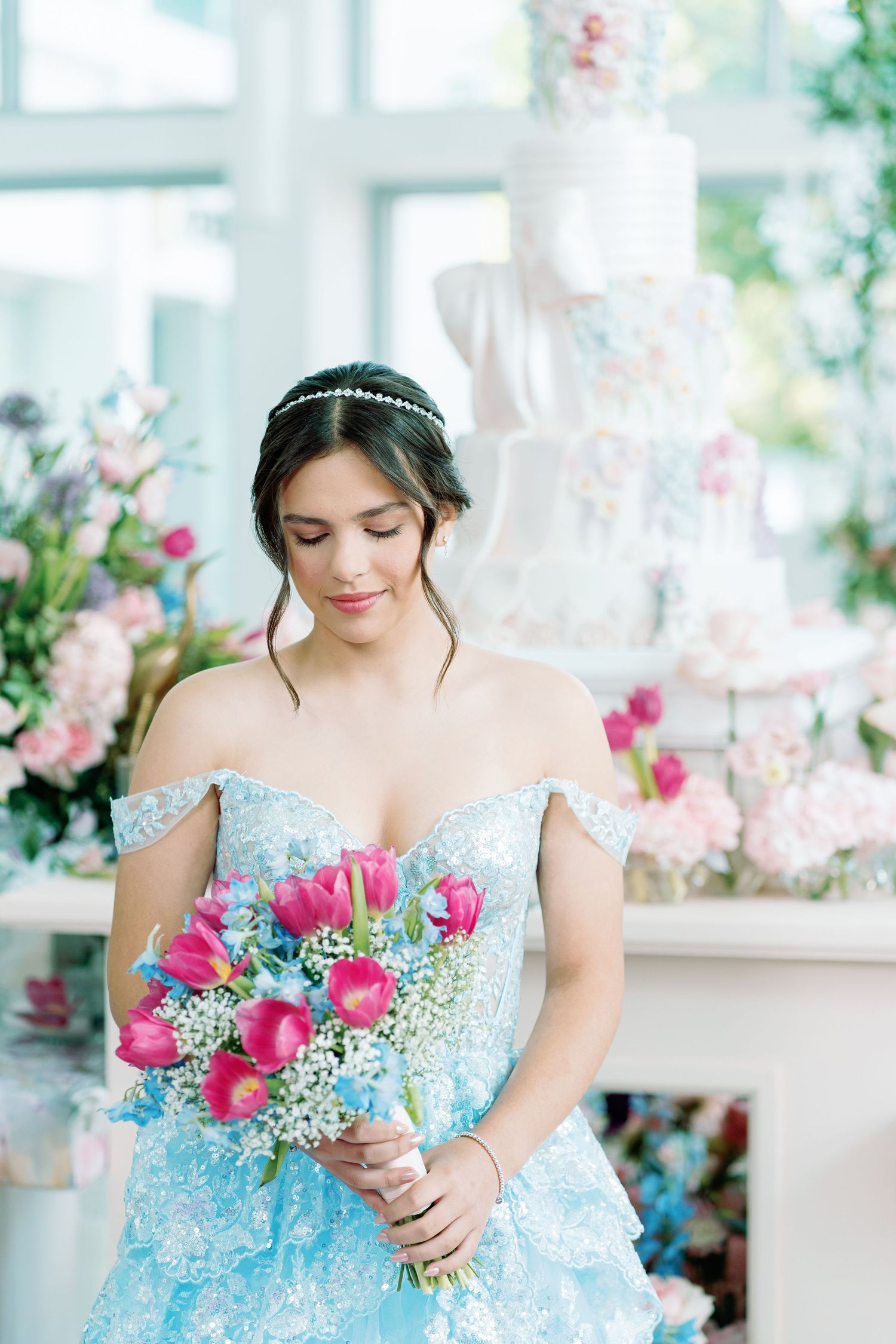 Light blue gown with pink flowers in a bright indoor setting with floral decorations.