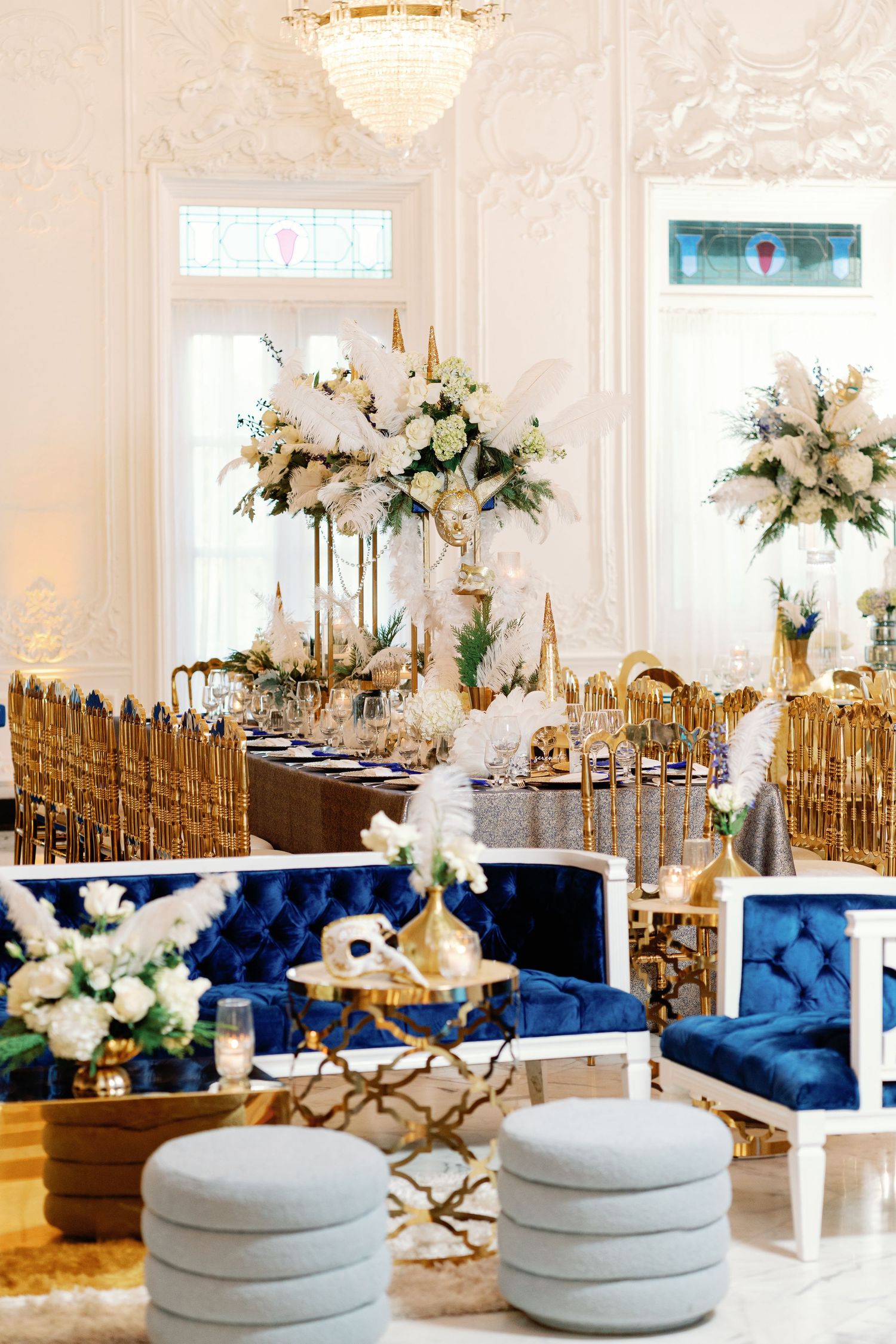 Modern wedding reception featuring navy blue seating and white floral centerpieces with gold accents.