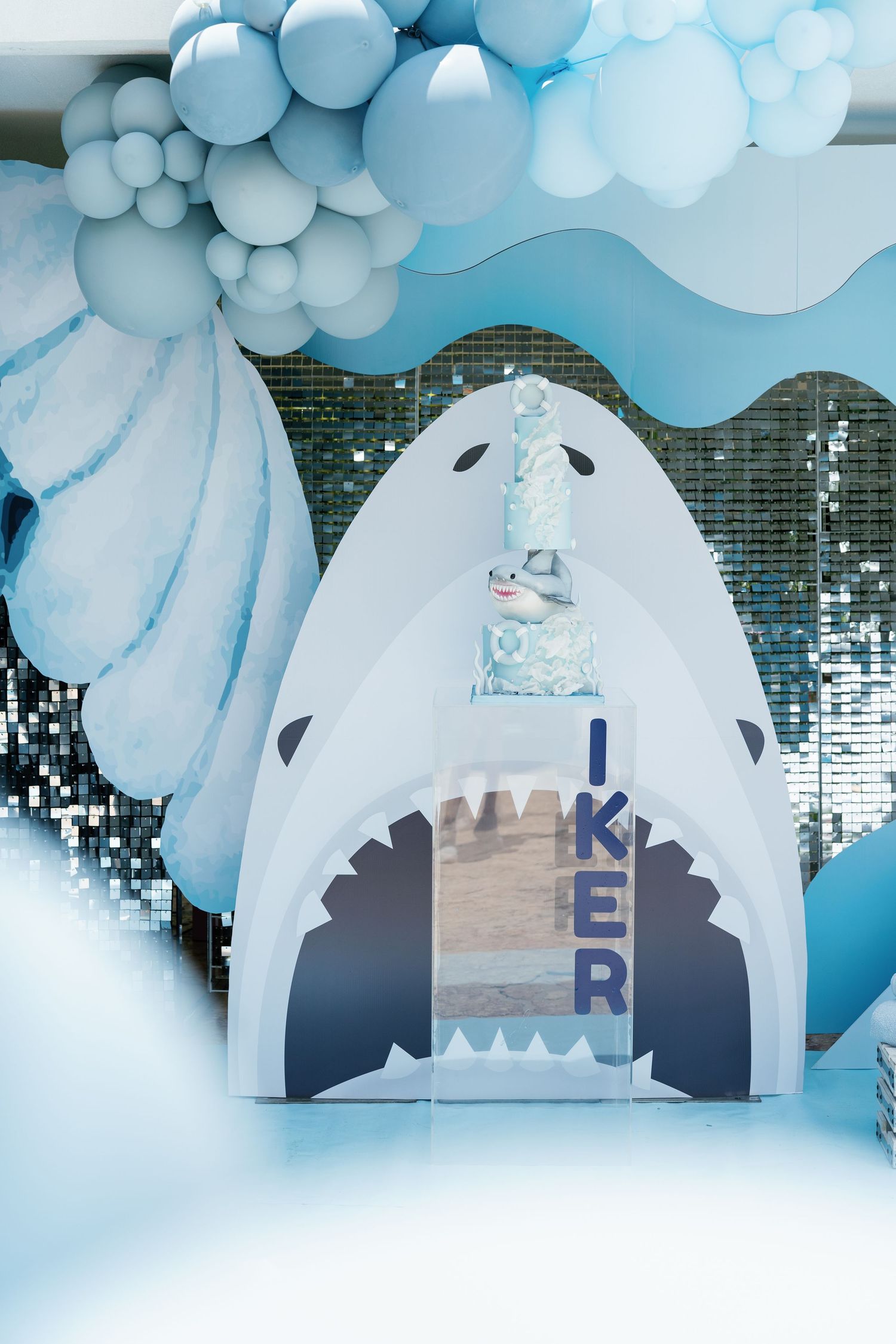 Winter wonderland themed party backdrop with white balloon arch and polar bear cutout.