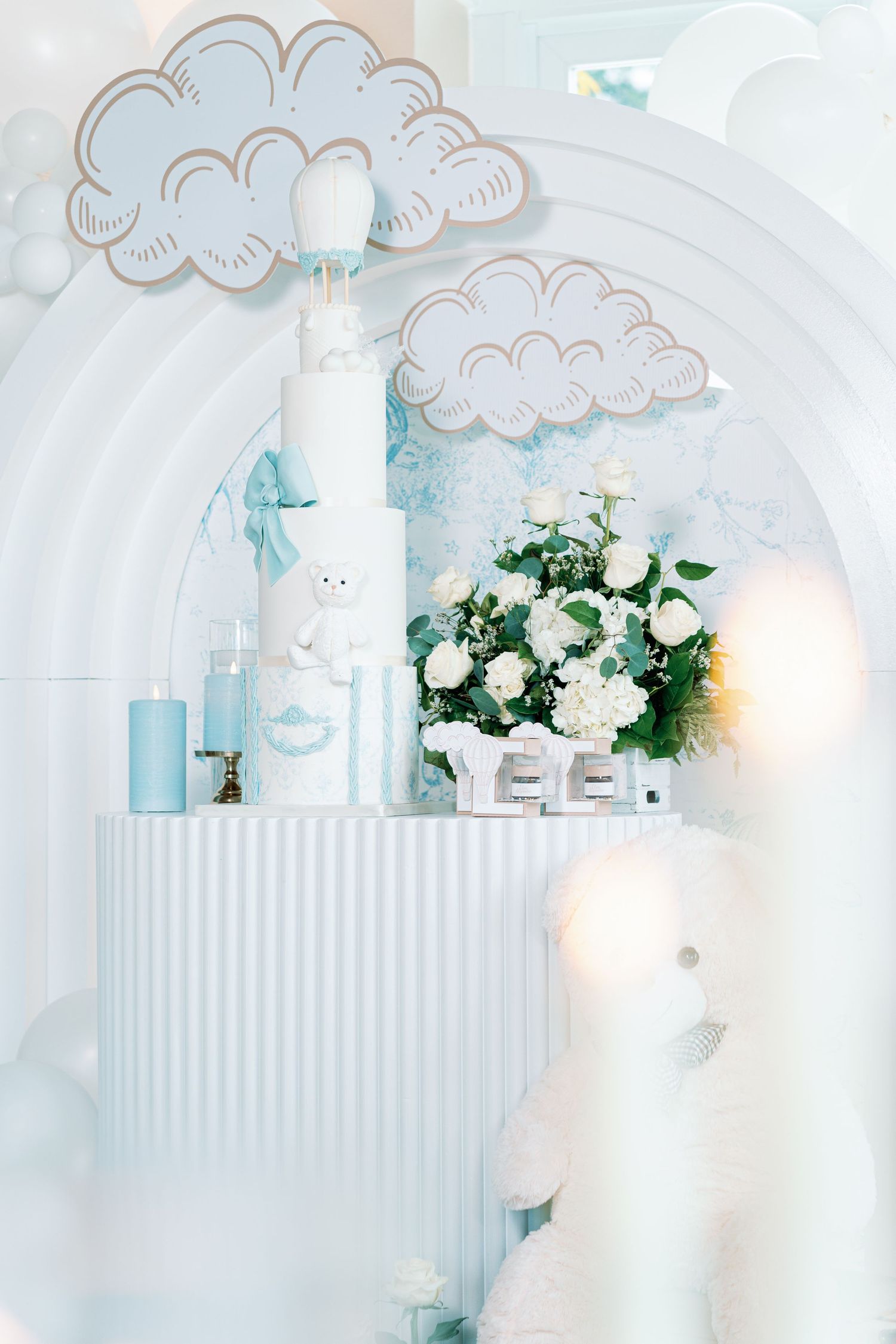 Cloud-themed white party decor with blue accents and floral arrangements creating an airy atmosphere.