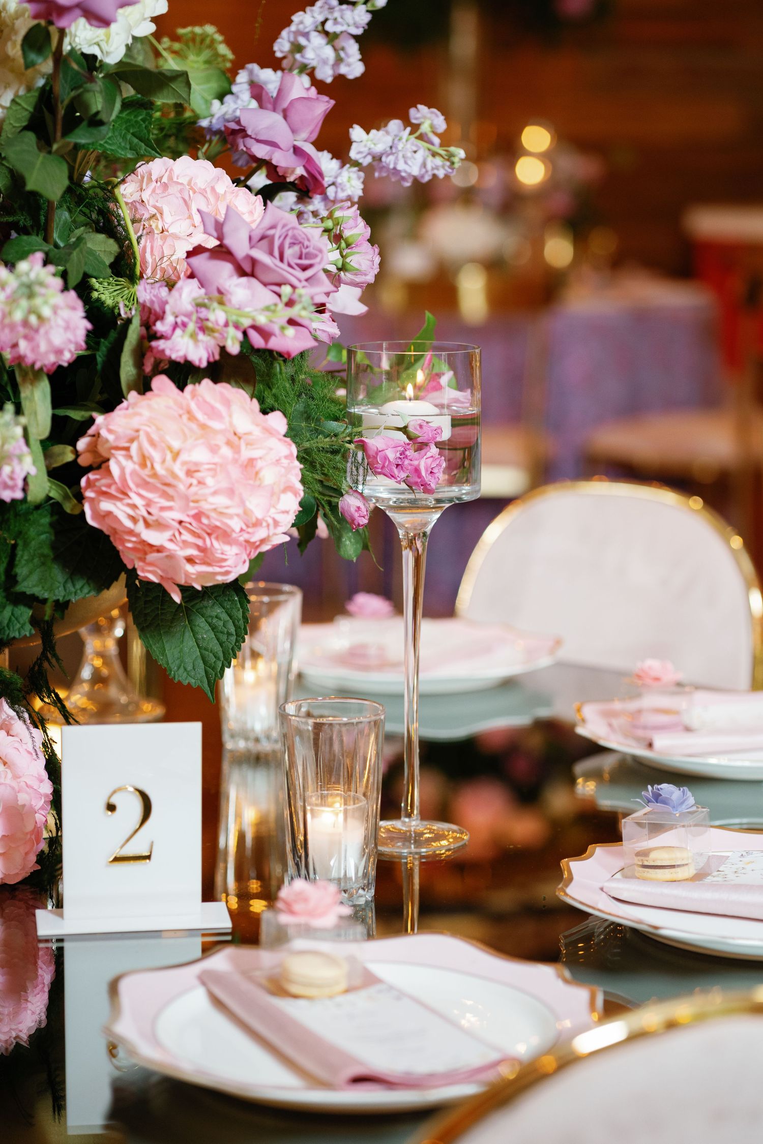 Romantic table settings with pink floral centerpieces, candles, and gold accents.