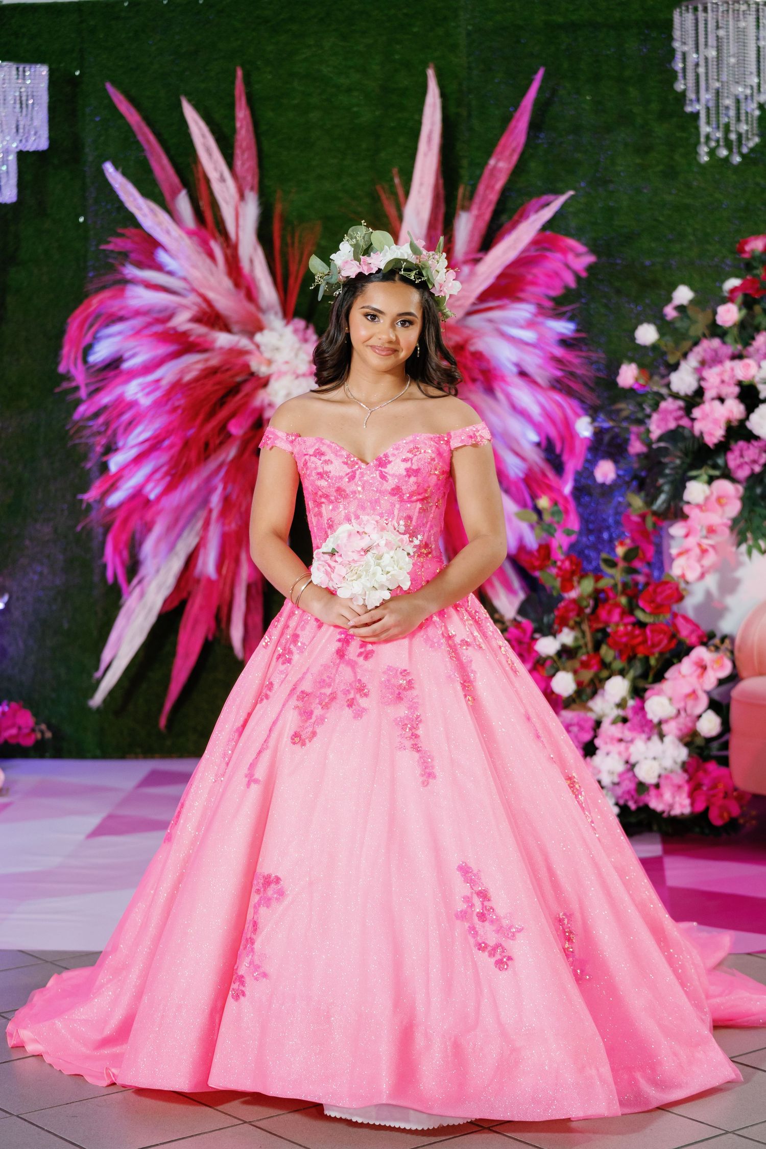 Dramatic pink ball gown with feather details photographed against a floral backdrop.
