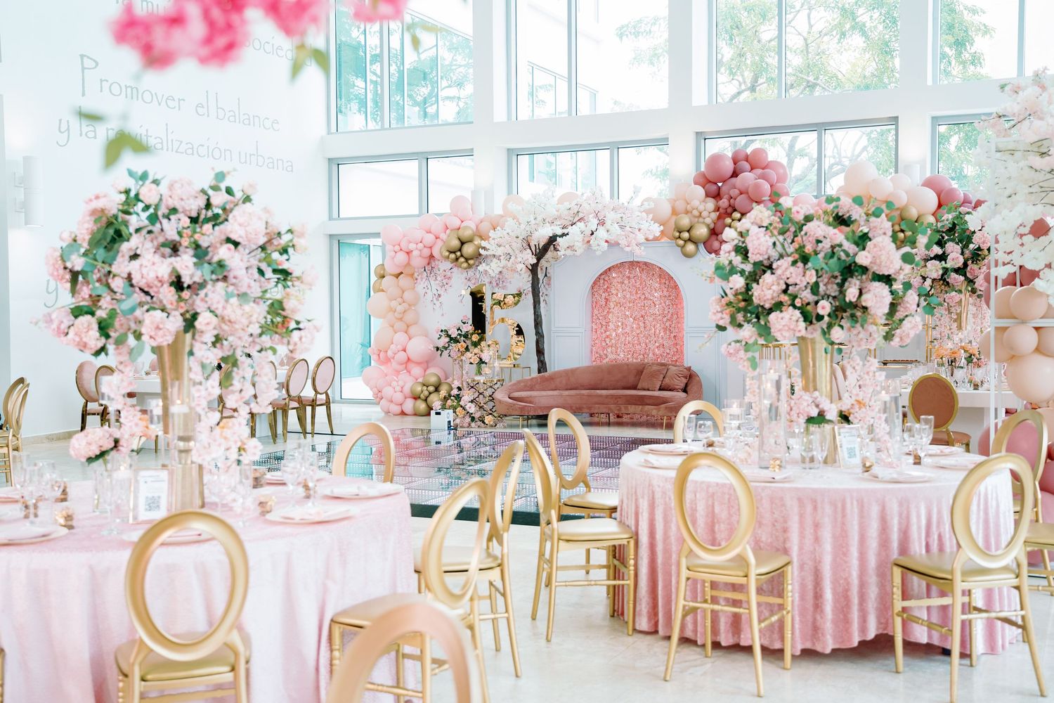 Elegant wedding reception venue with pink floral centerpieces and gold accents.