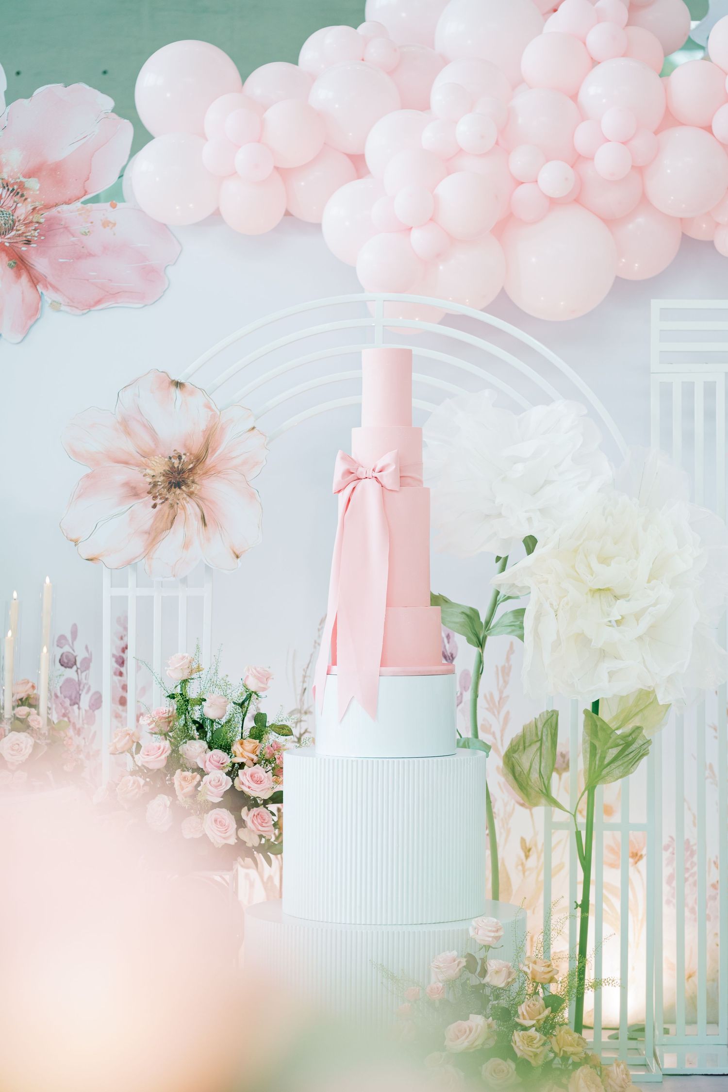 Whimsical pink balloon arch and floral decorations with pastel accents for a dreamy celebration setup.