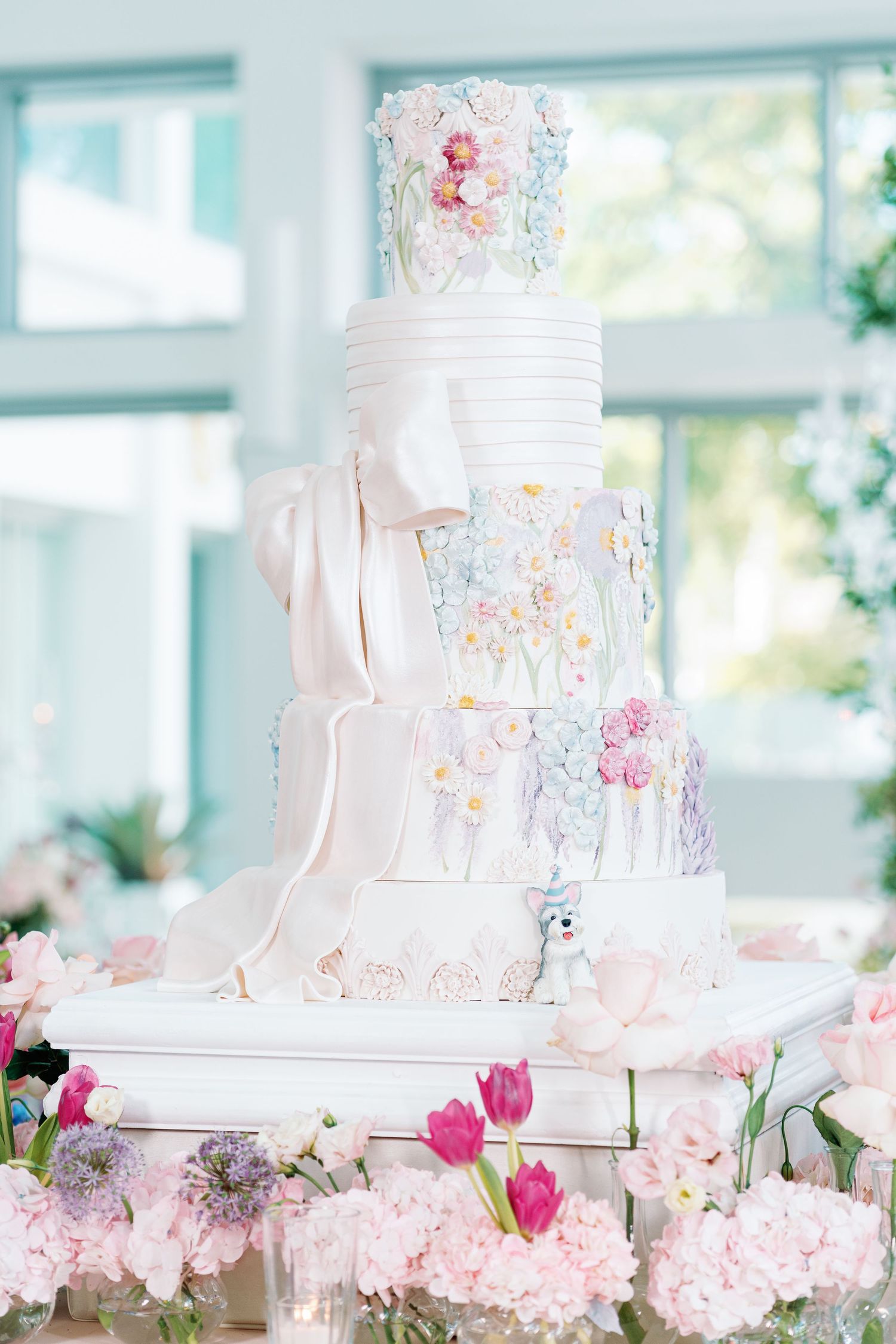 Elegant white wedding cake decorated with delicate pink sugar flowers.