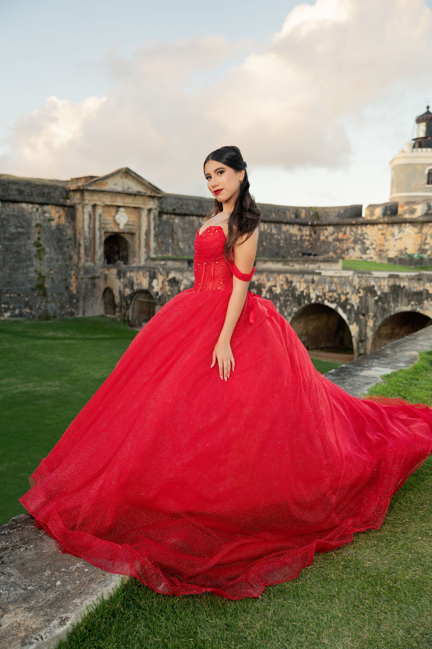 Dramatic red ball gown photo session at historic stone fortress during sunset.