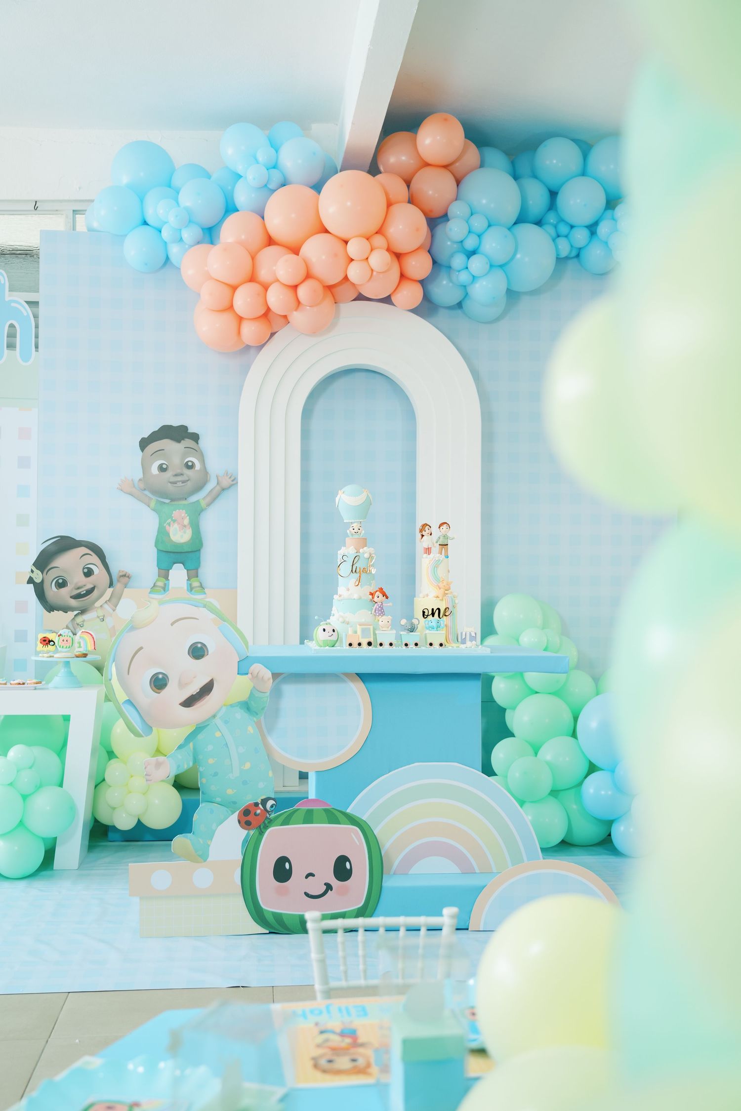 Whimsical baby shower setup with pastel balloons, cute animal decorations, and rainbow accents.