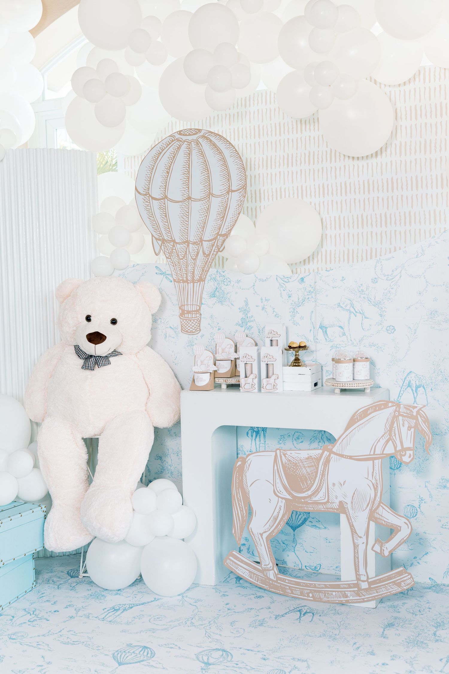 Soft blue and white nursery decor with teddy bears, hot air balloons, and rocking horse accents.