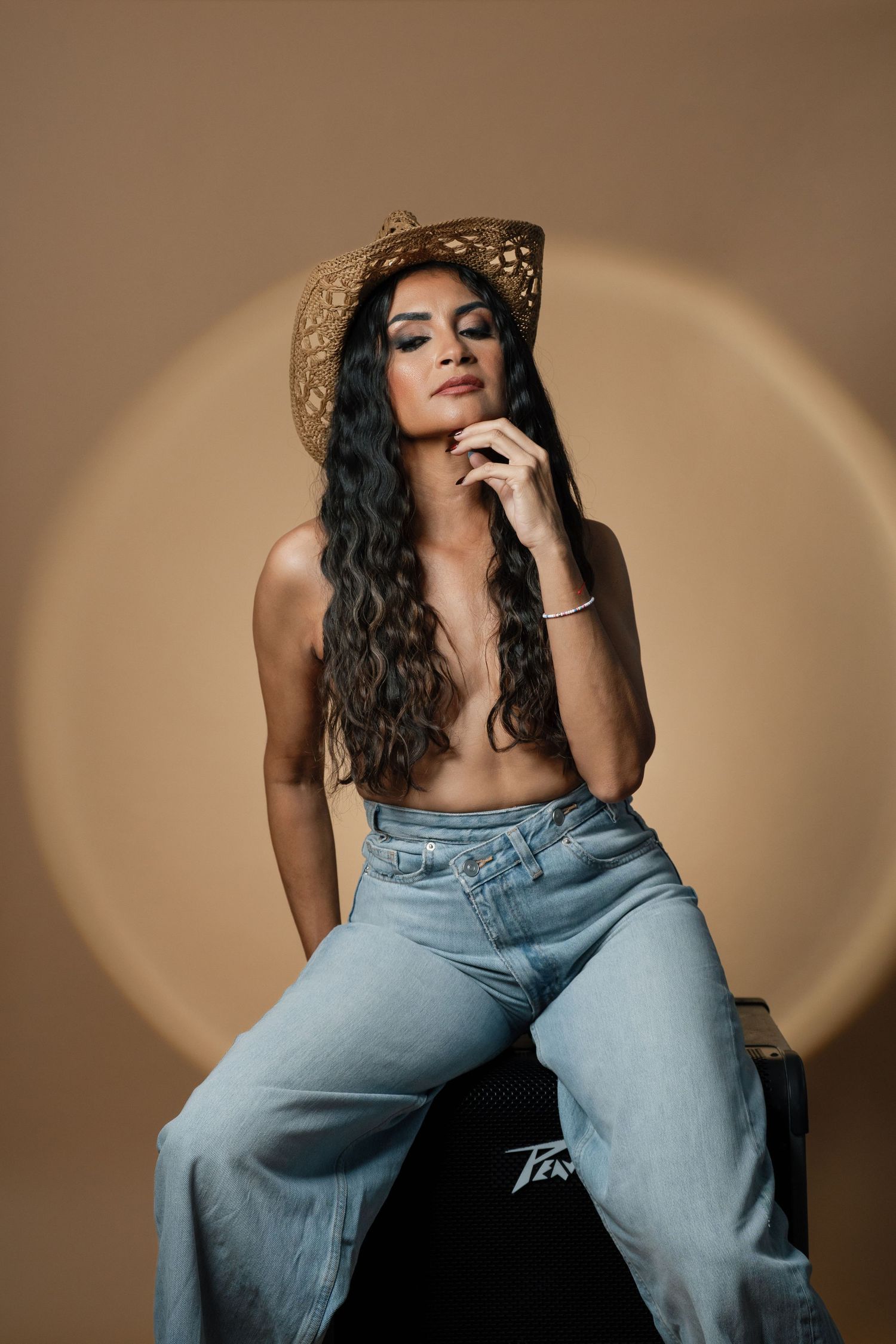 Fashion portrait of woman in denim jeans and hat against warm brown background in artistic poses.